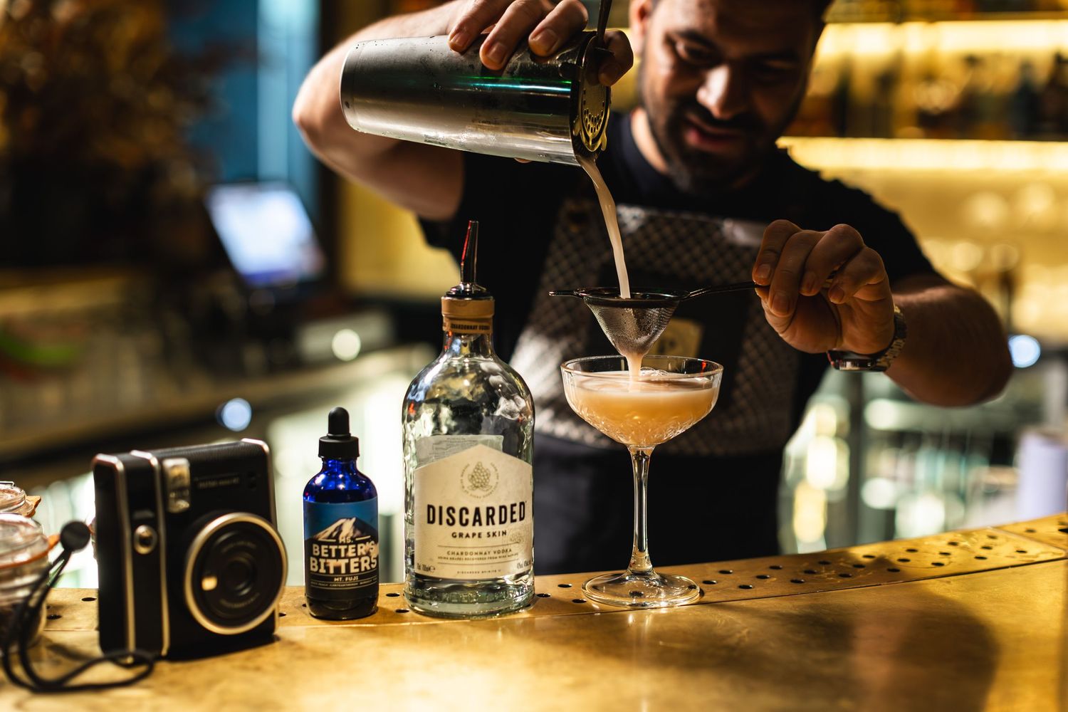 Bartender pouring a craft cocktail into a coupe glass with precision.