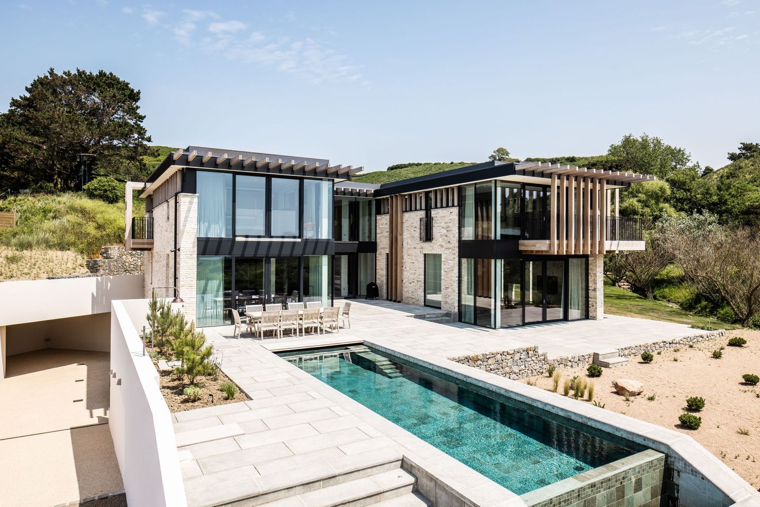 Modern luxury villa with infinity pool and minimalist architecture set in coastal landscape.
