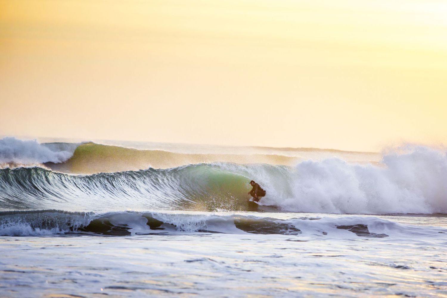Golden sunset over ocean waves breaking along the shoreline.