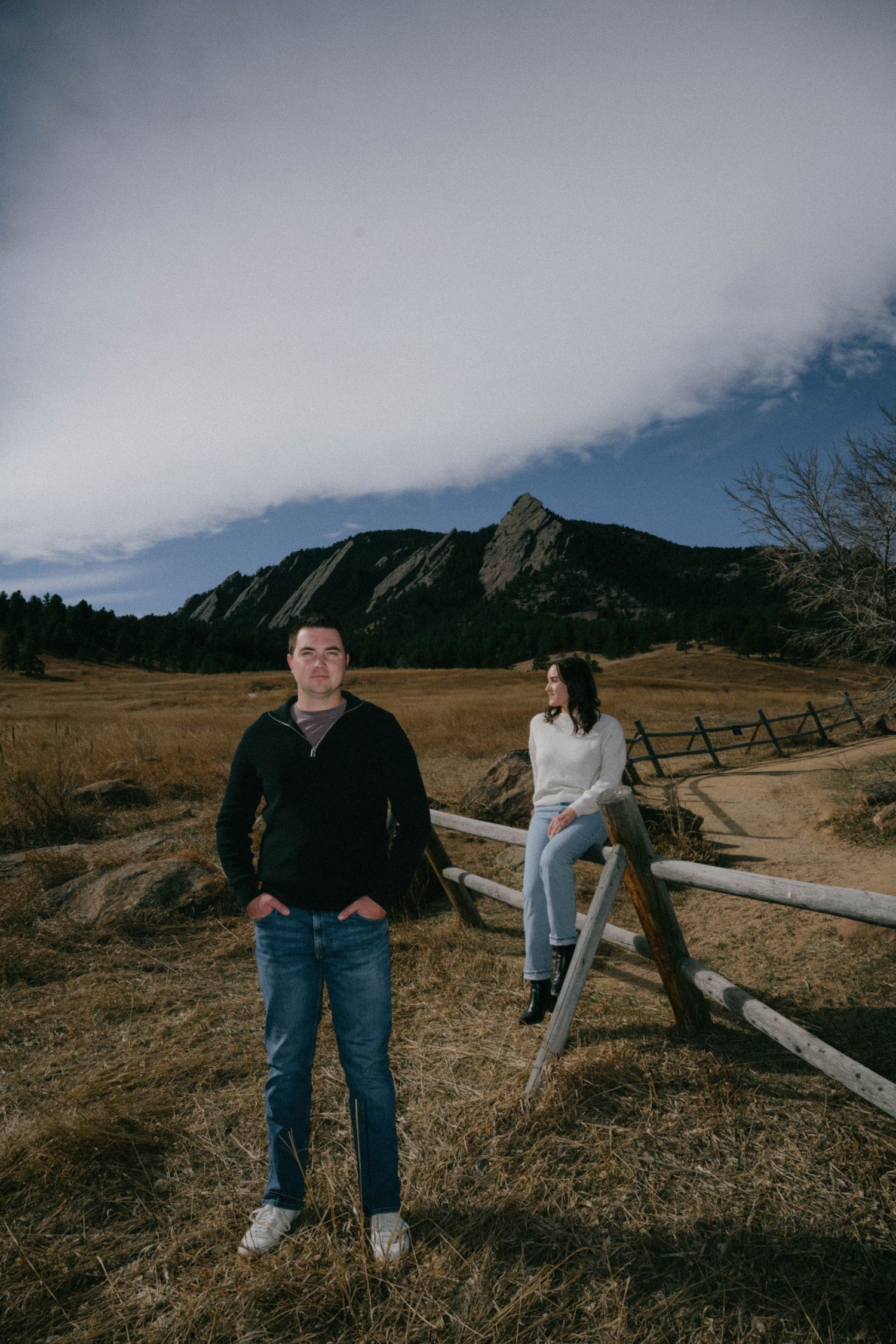 Couple poses at Chautauqua Park with iconic Boulder Colorado Flatirons mountains in background at dusk.