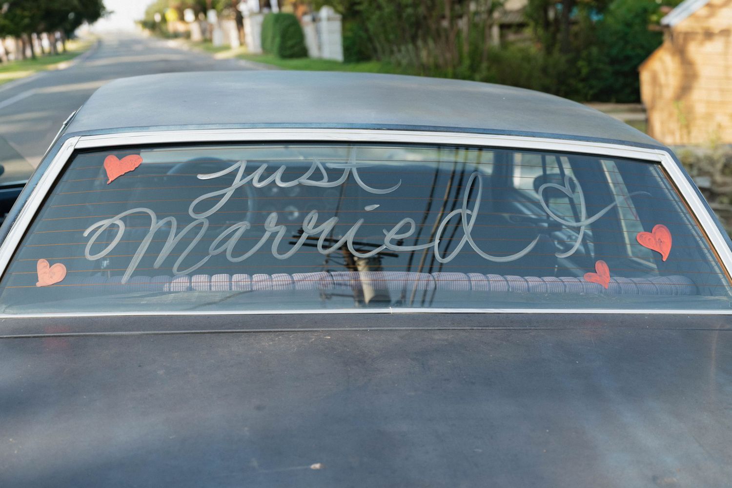Vintage car rear window decorated with Just Married text and red hearts for a wedding celebration.