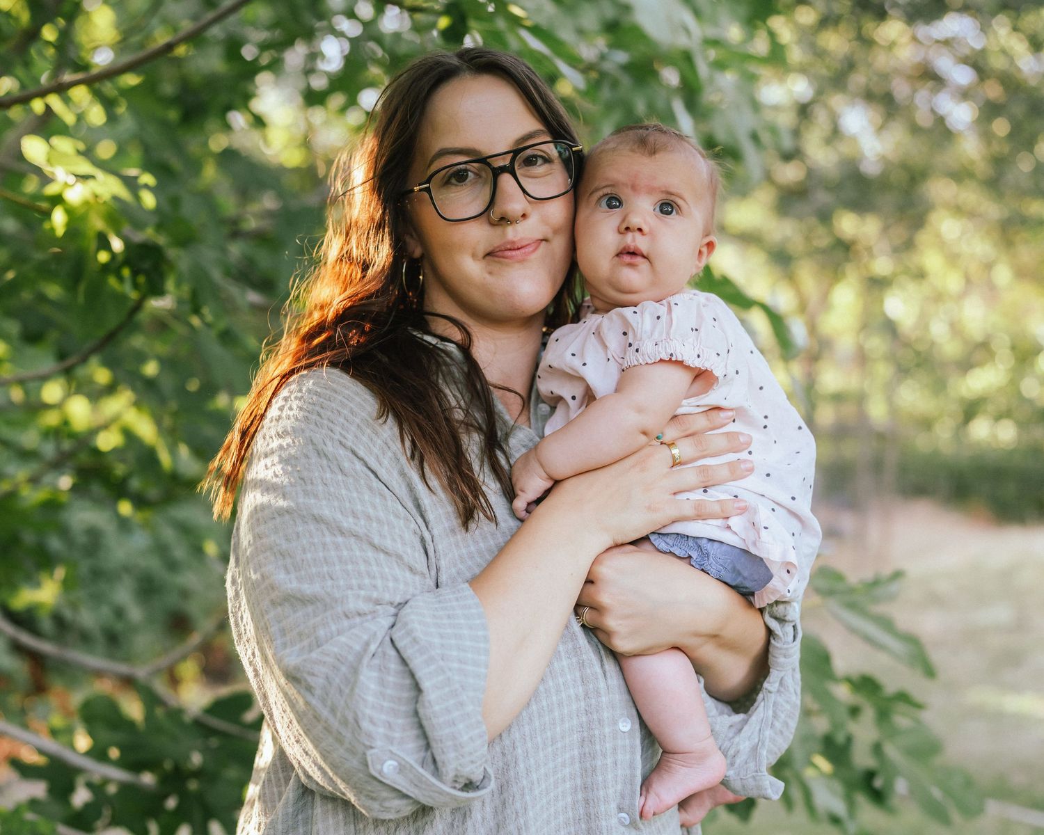 Parent and baby sharing tender moment in outdoor garden setting.