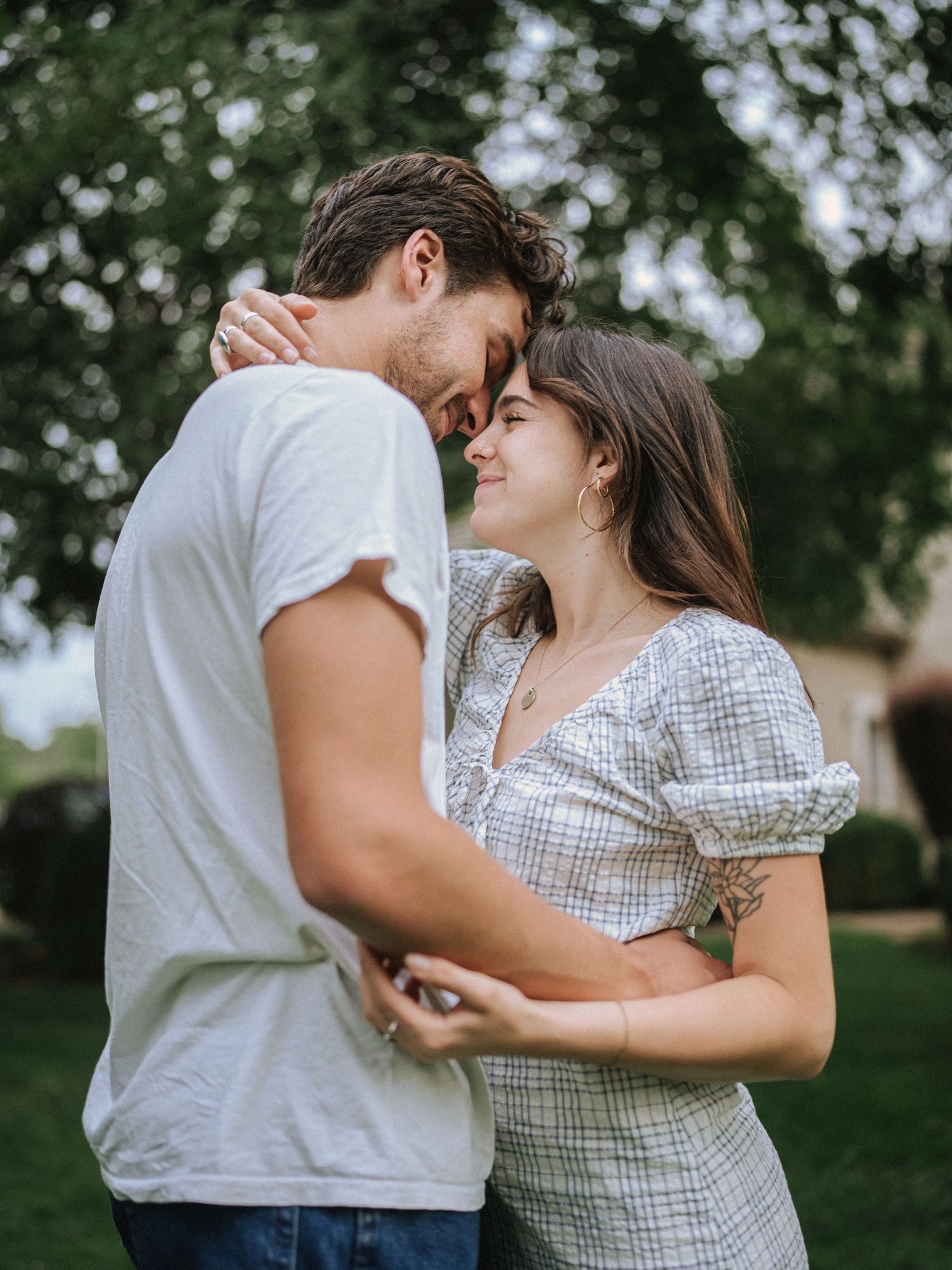 Couple dancing together in a garden setting wearing casual summer outfits.