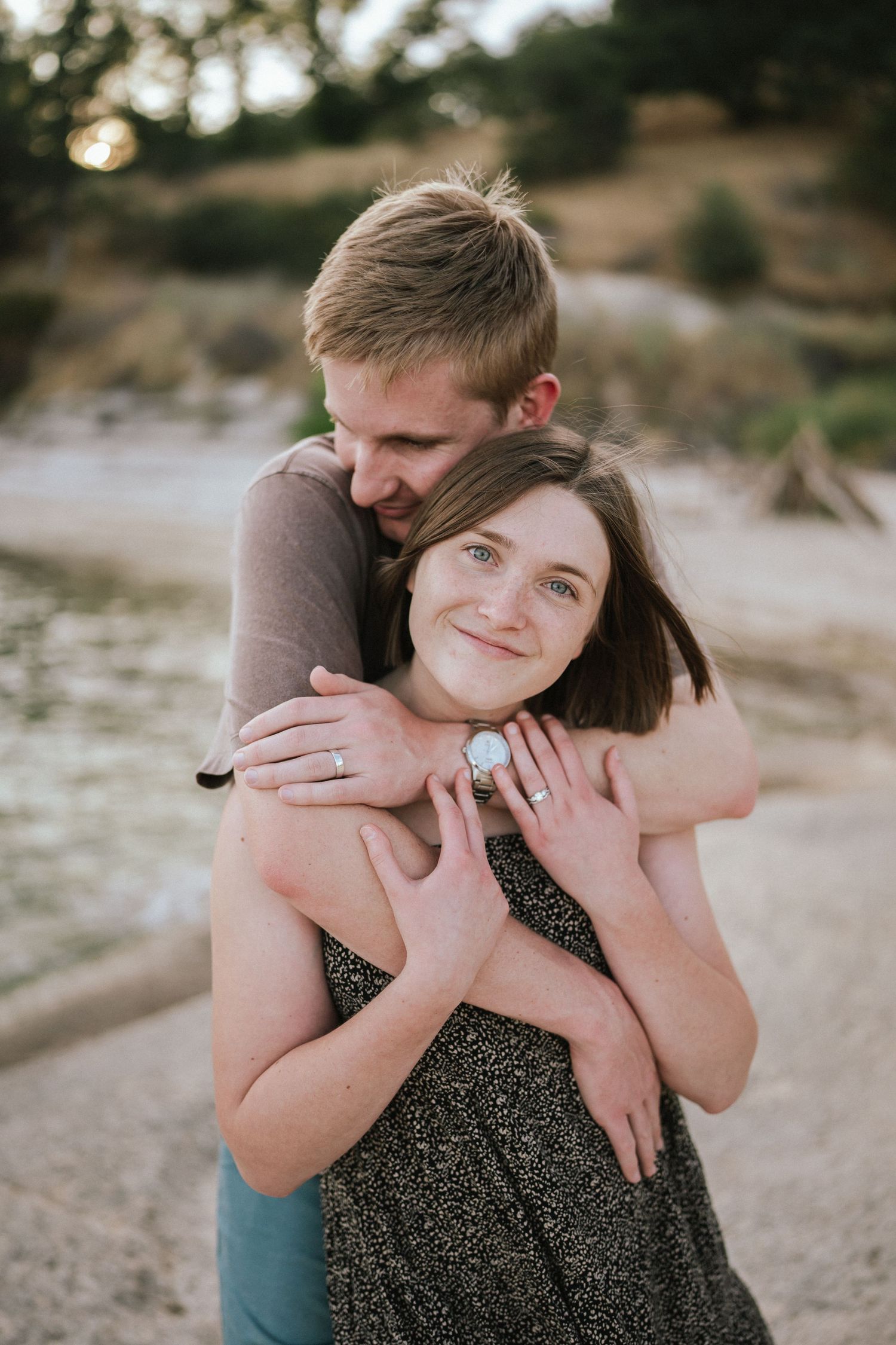 Couple embracing on a beach during a sunset photoshoot session.