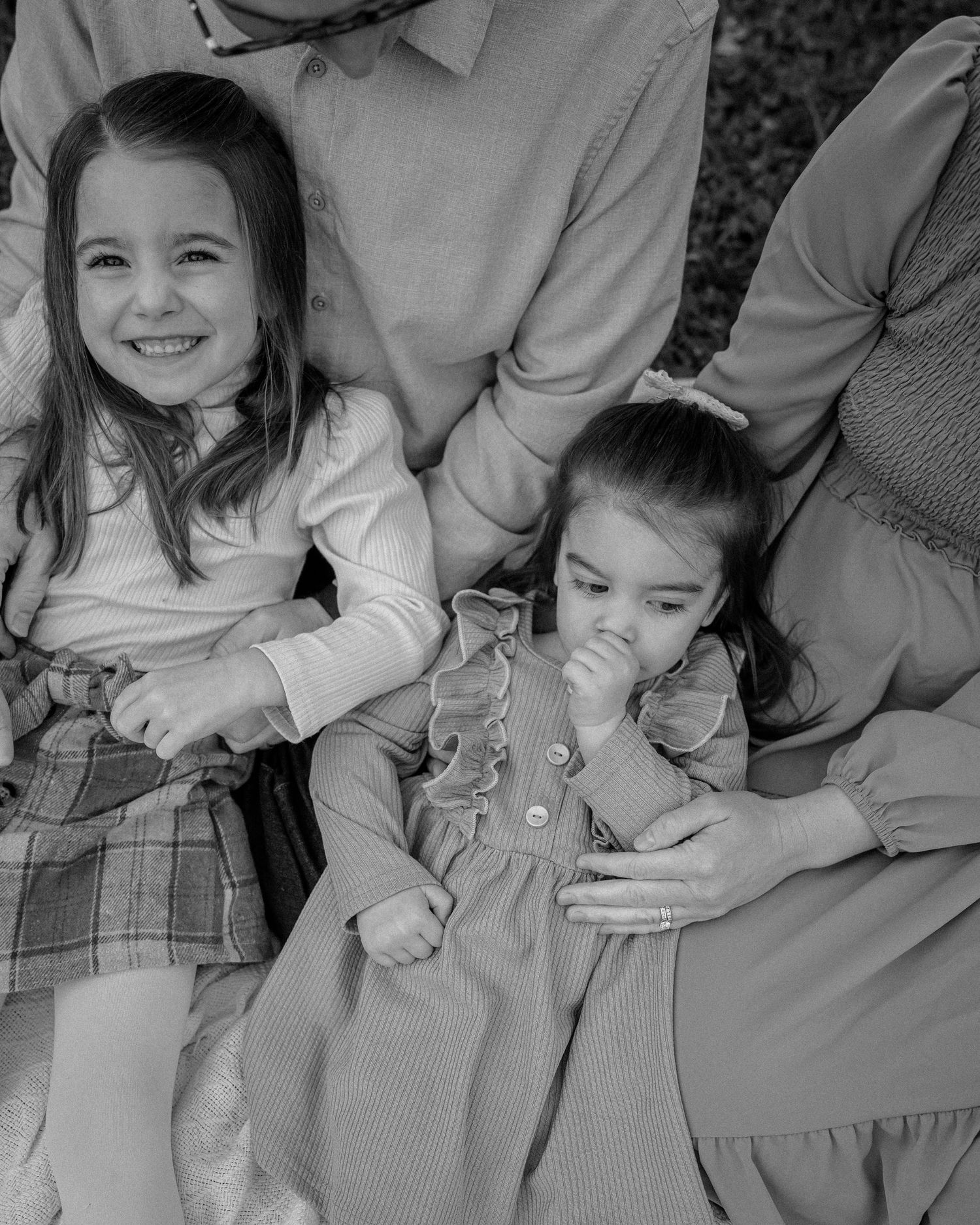 Two children in formal attire share a candid black and white moment together.