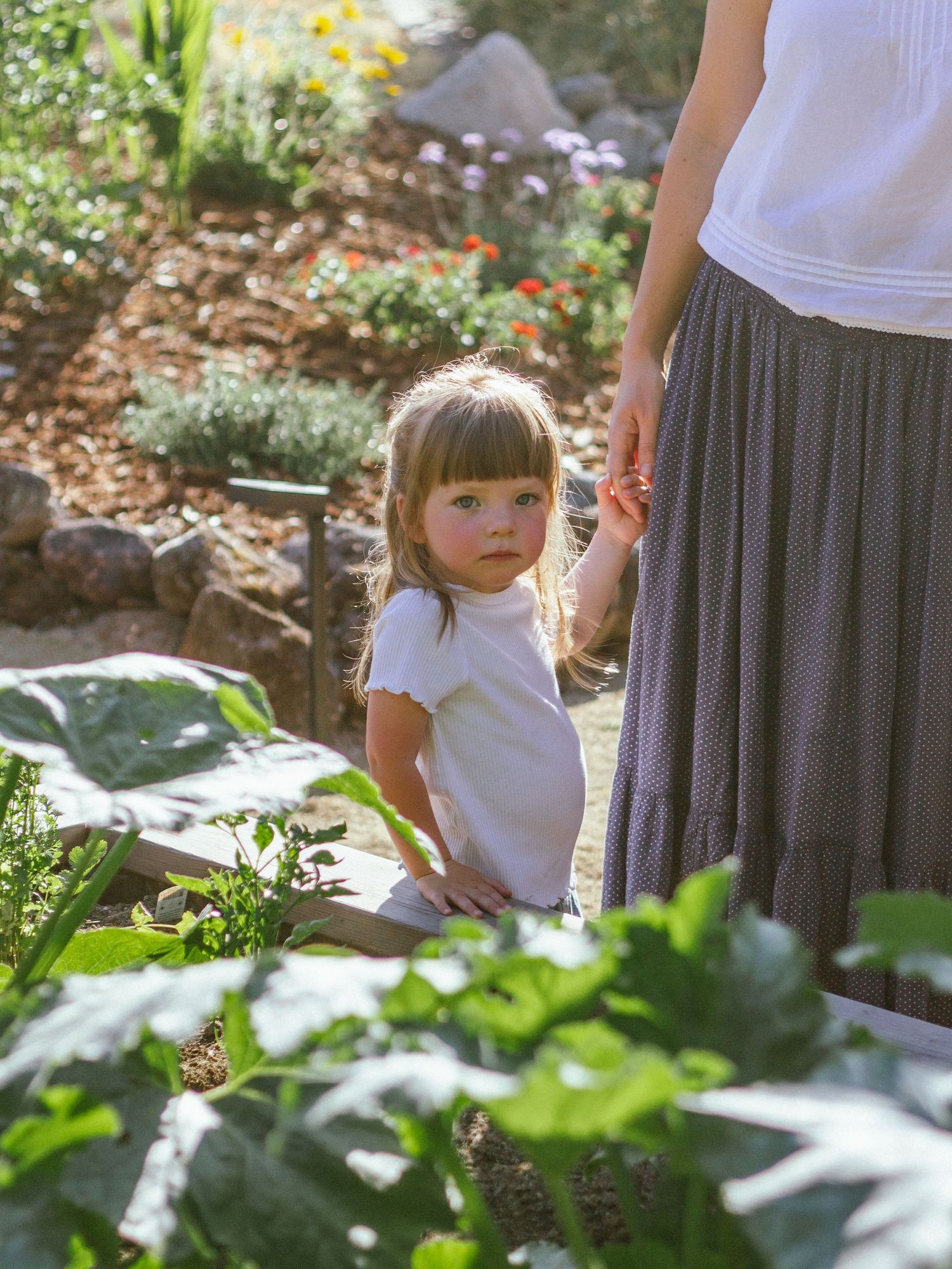 Sunlit garden moments captured with flowing skirts and natural foliage.