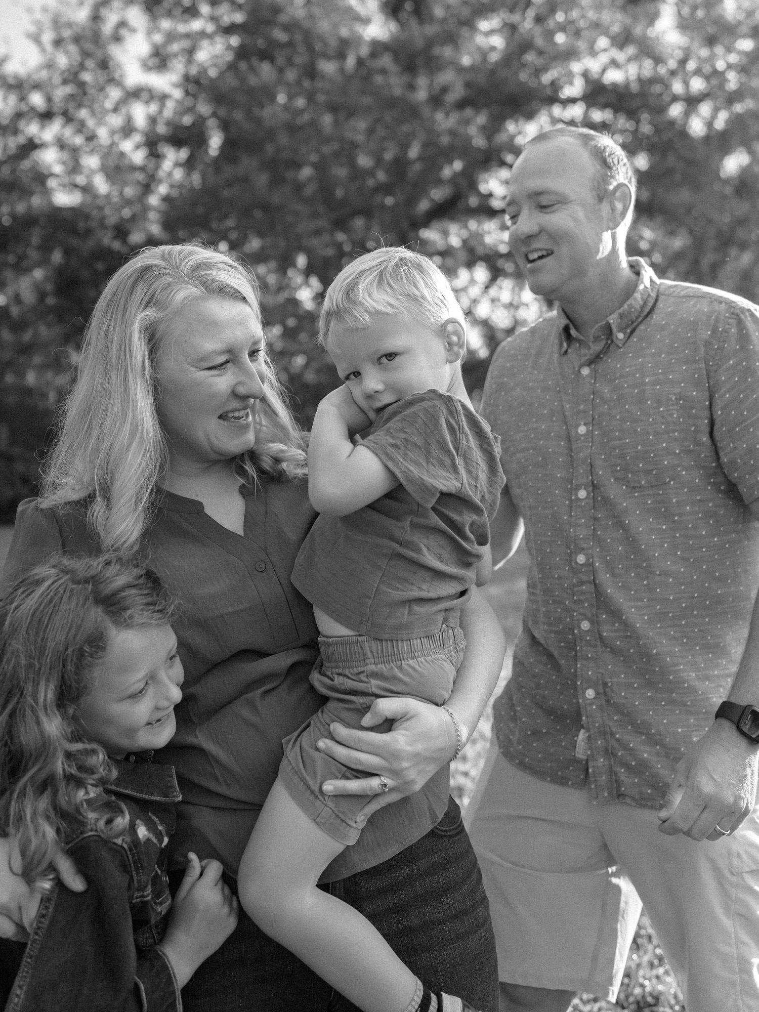 Black and white candid family photos showing joyful outdoor interactions.