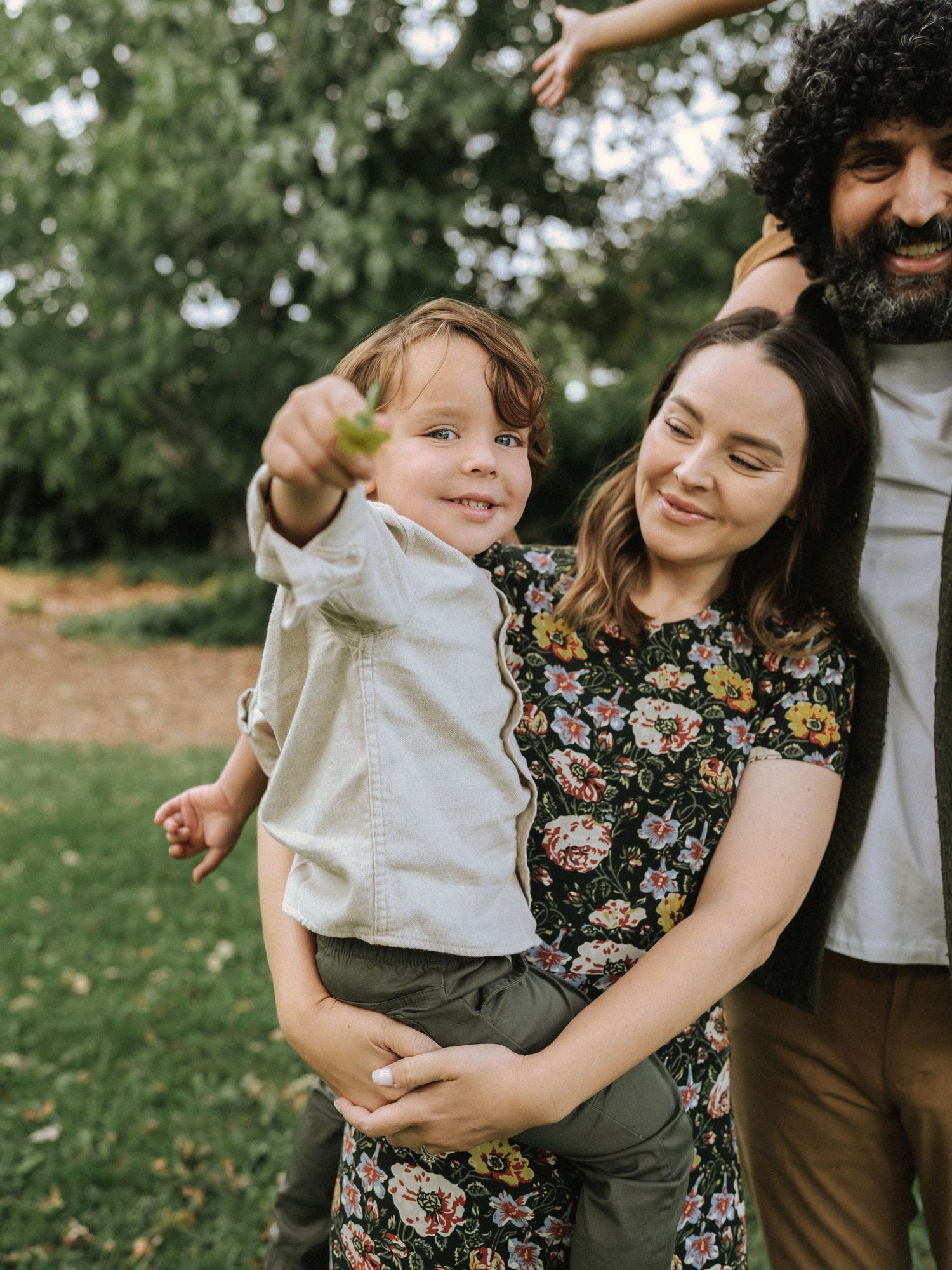 A family shares a joyful outdoor moment together in a garden setting with natural greenery in the background.
