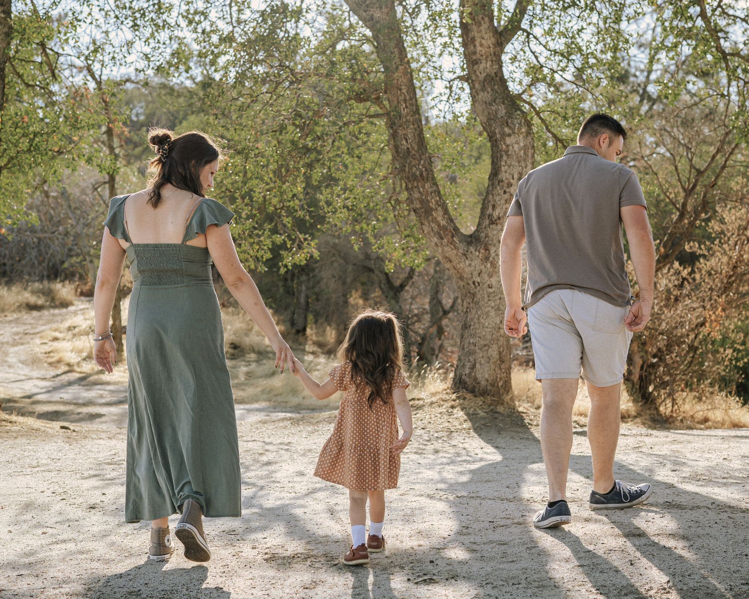 People walking together on a sandy path surrounded by natural vegetation.