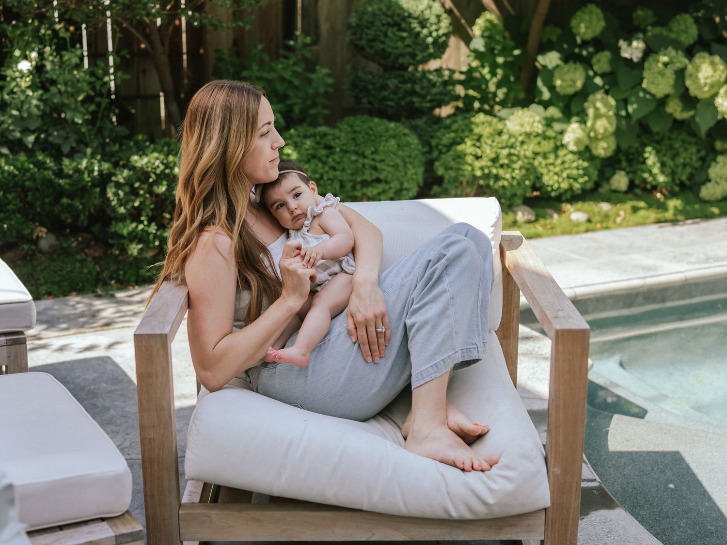 A tender moment shared on a cushioned outdoor chair by a pool.