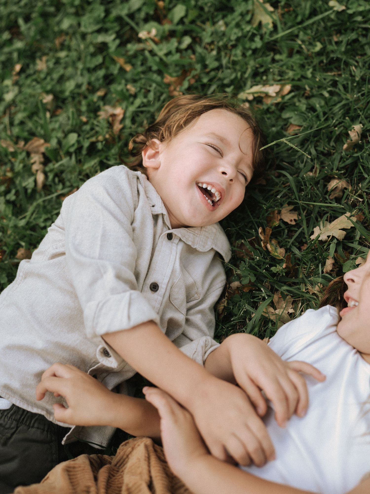 Candid shots of joyful laughter while lying on grass and fallen leaves.