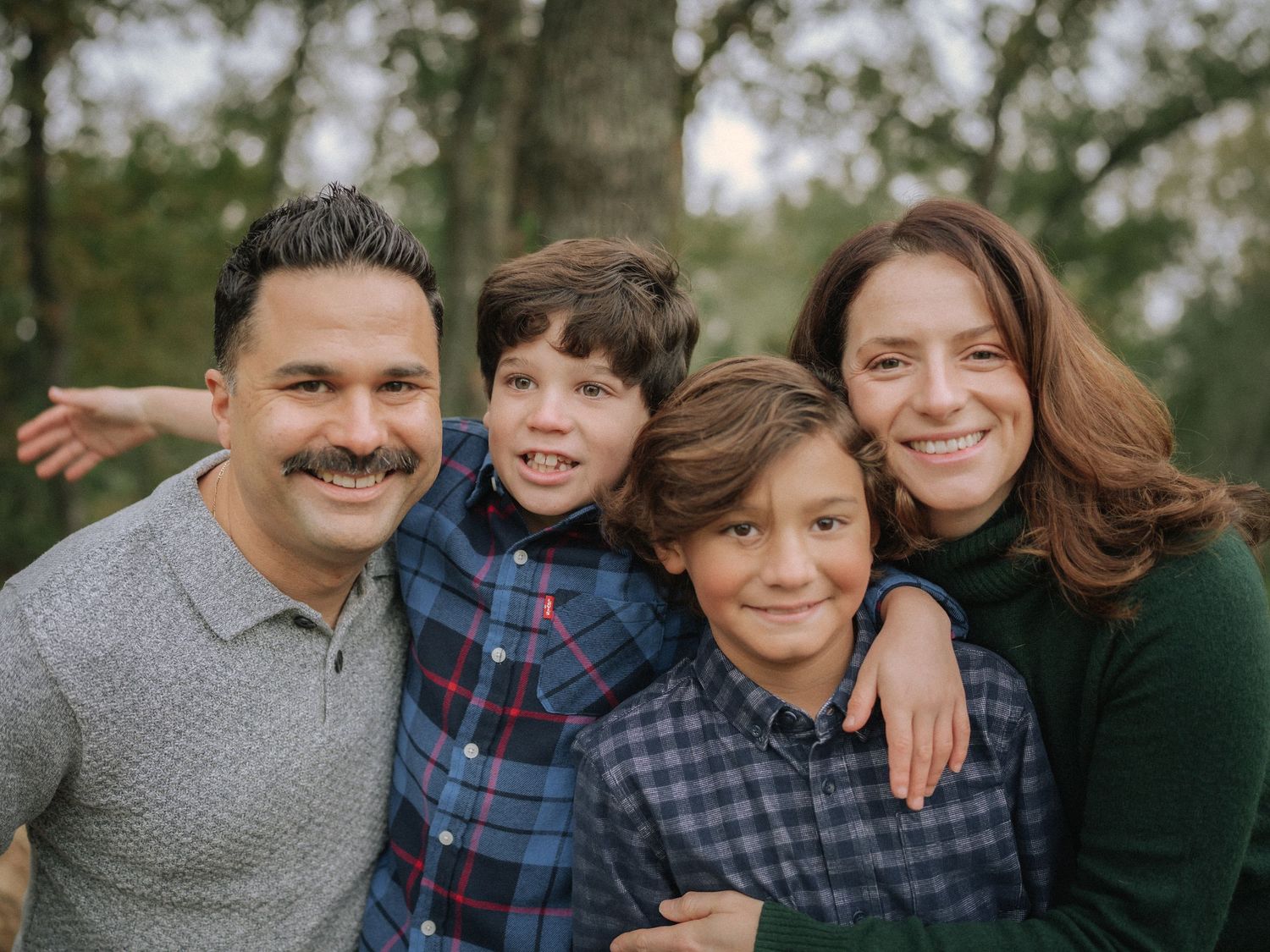 A family of four poses together for a casual outdoor portrait.