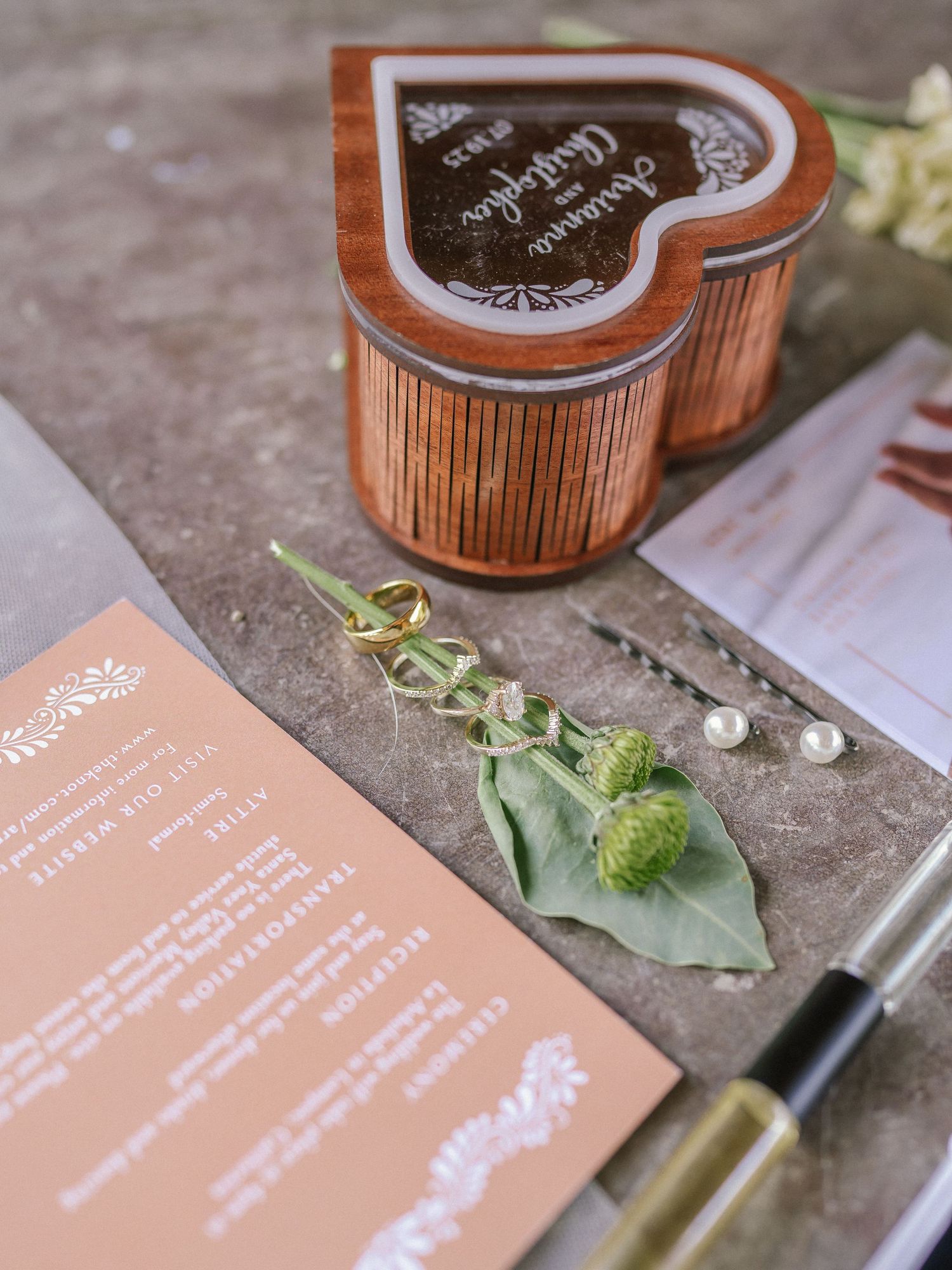 Wedding stationery and decorative wooden box arranged with greenery.