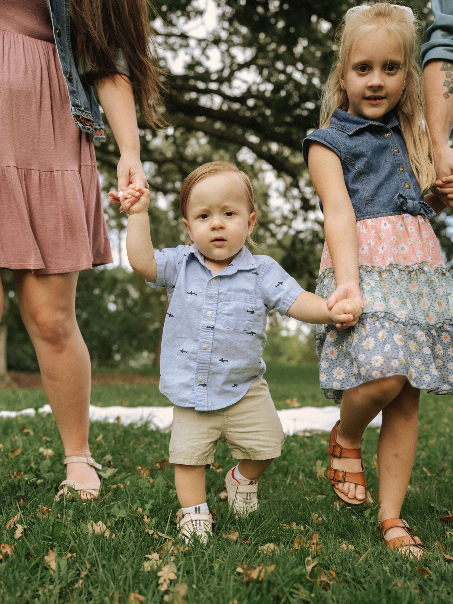 Children and adults walking together on grass wearing casual summer clothing.