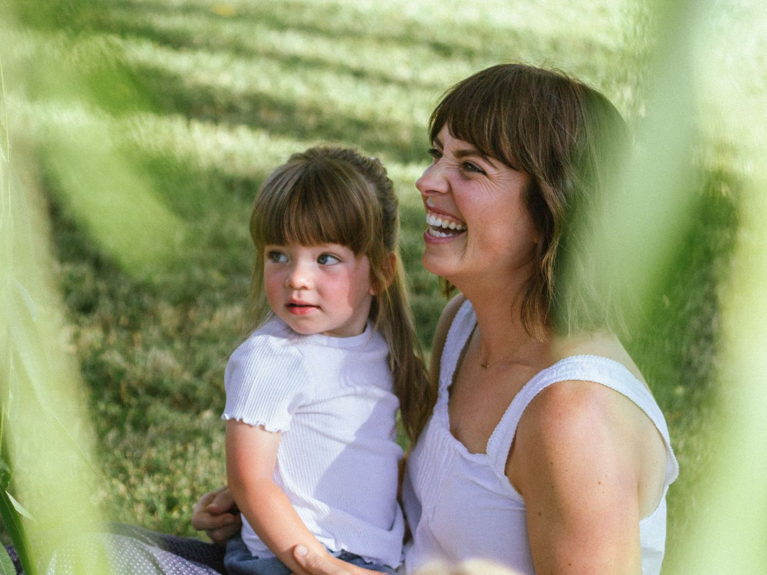 Mother and child sharing joyful moments together in white summer outfits.