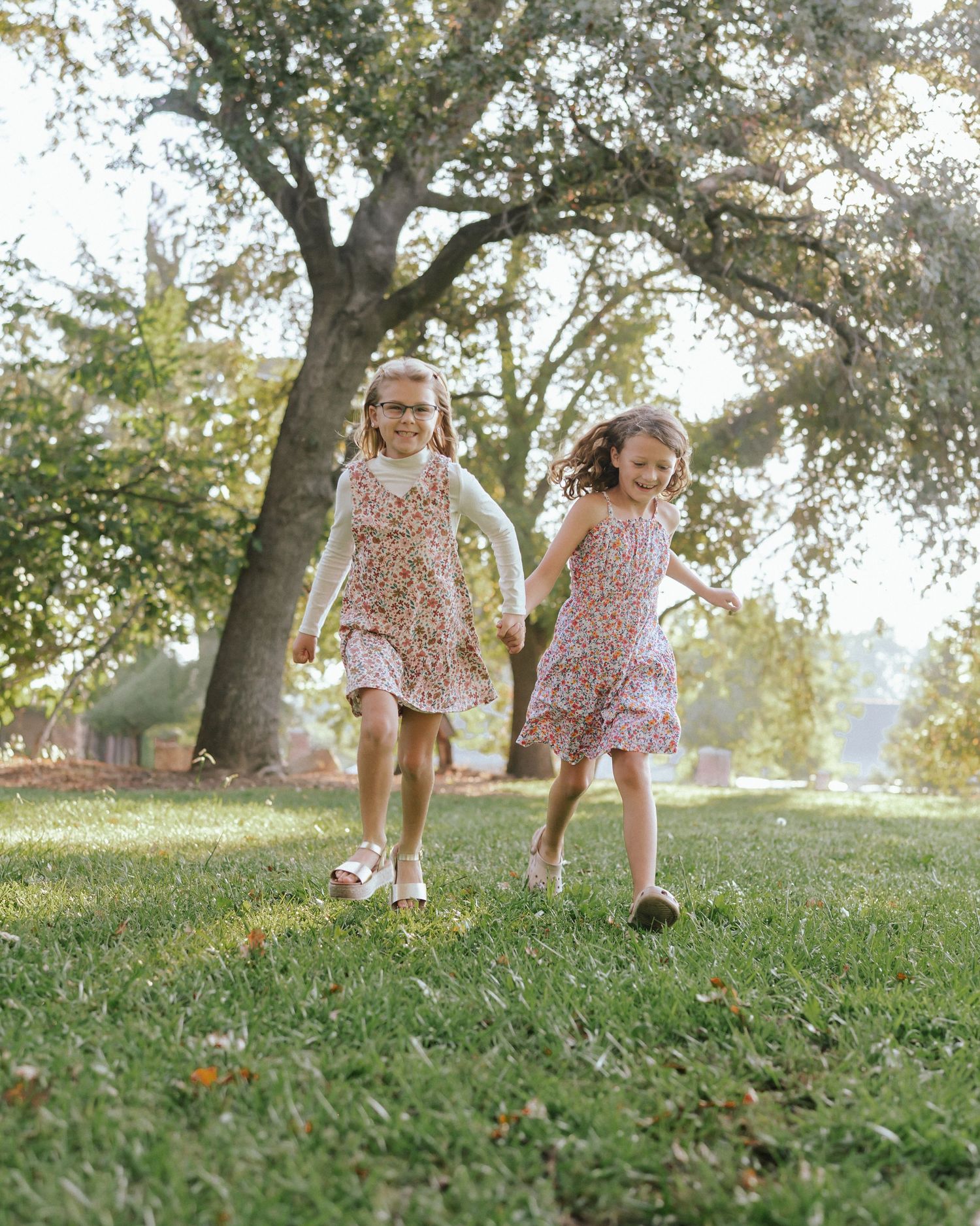 Children running and playing on a grassy hill during a sunny afternoon.