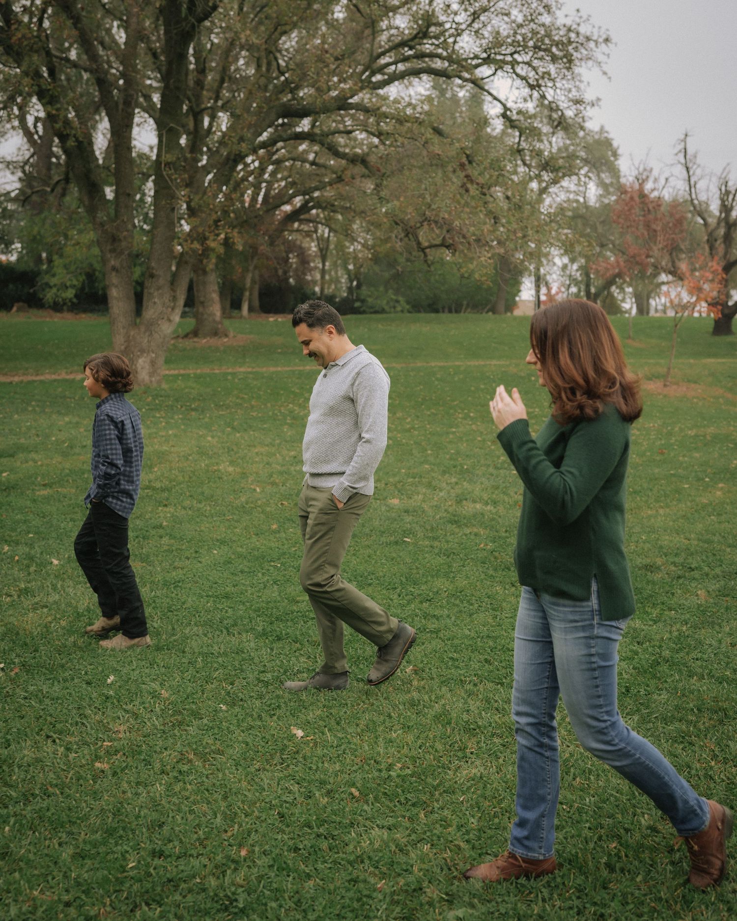 A playful sequence of people jumping and moving across a grassy lawn on a sunny day.