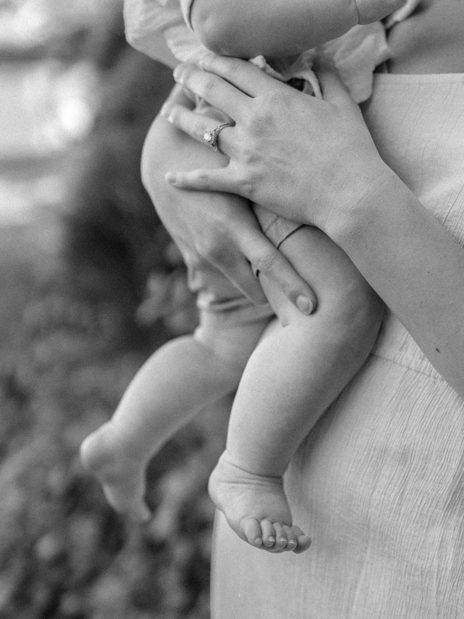 Black and white close-up of small bare feet and hands.