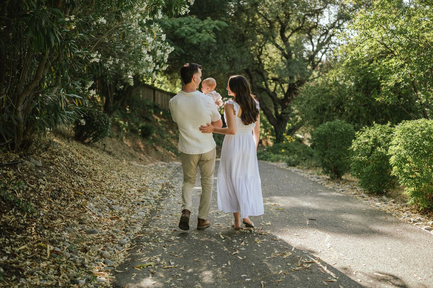 Family walking together on a tree-lined path during golden hour.