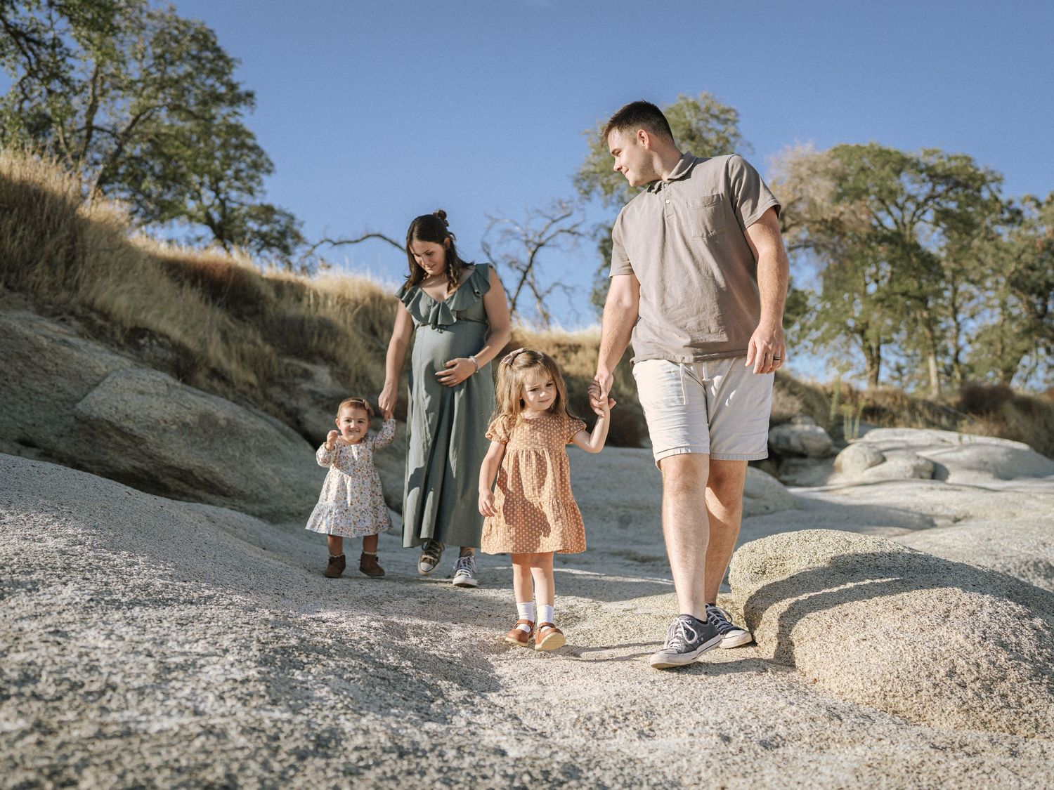 Family walking together on rocky terrain during a sunny outdoor adventure.