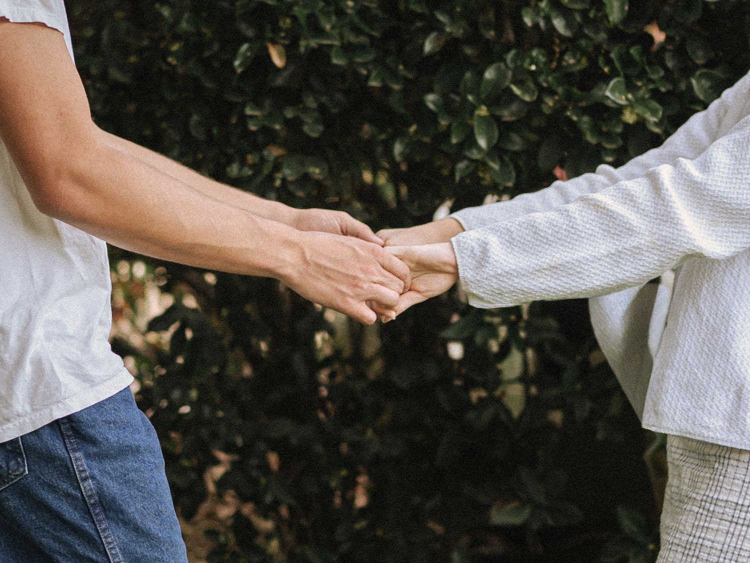 Close-up of hands reaching out to connect in an outdoor setting.