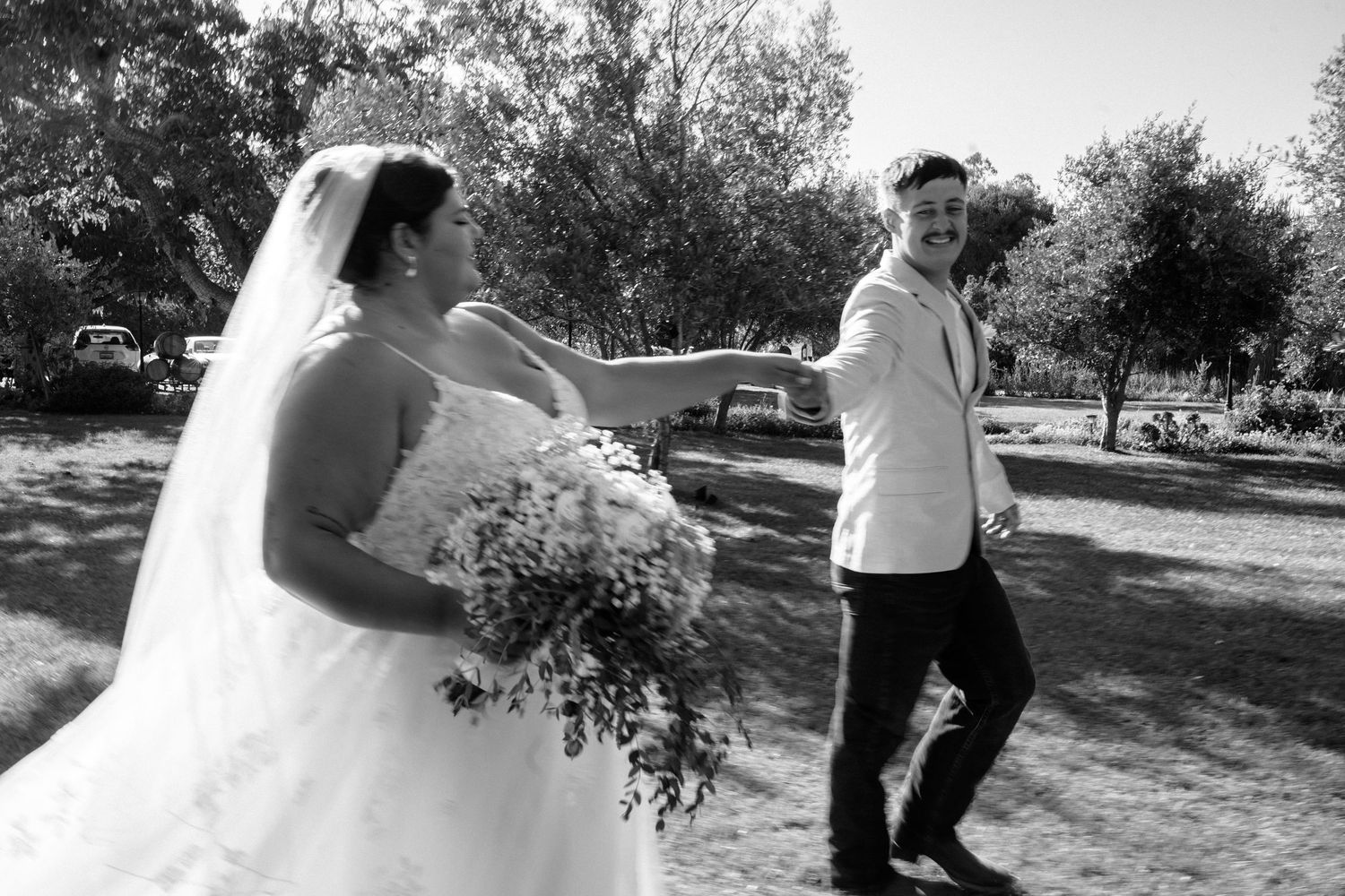 Wedding couple sharing a playful moment outdoors in black and white.