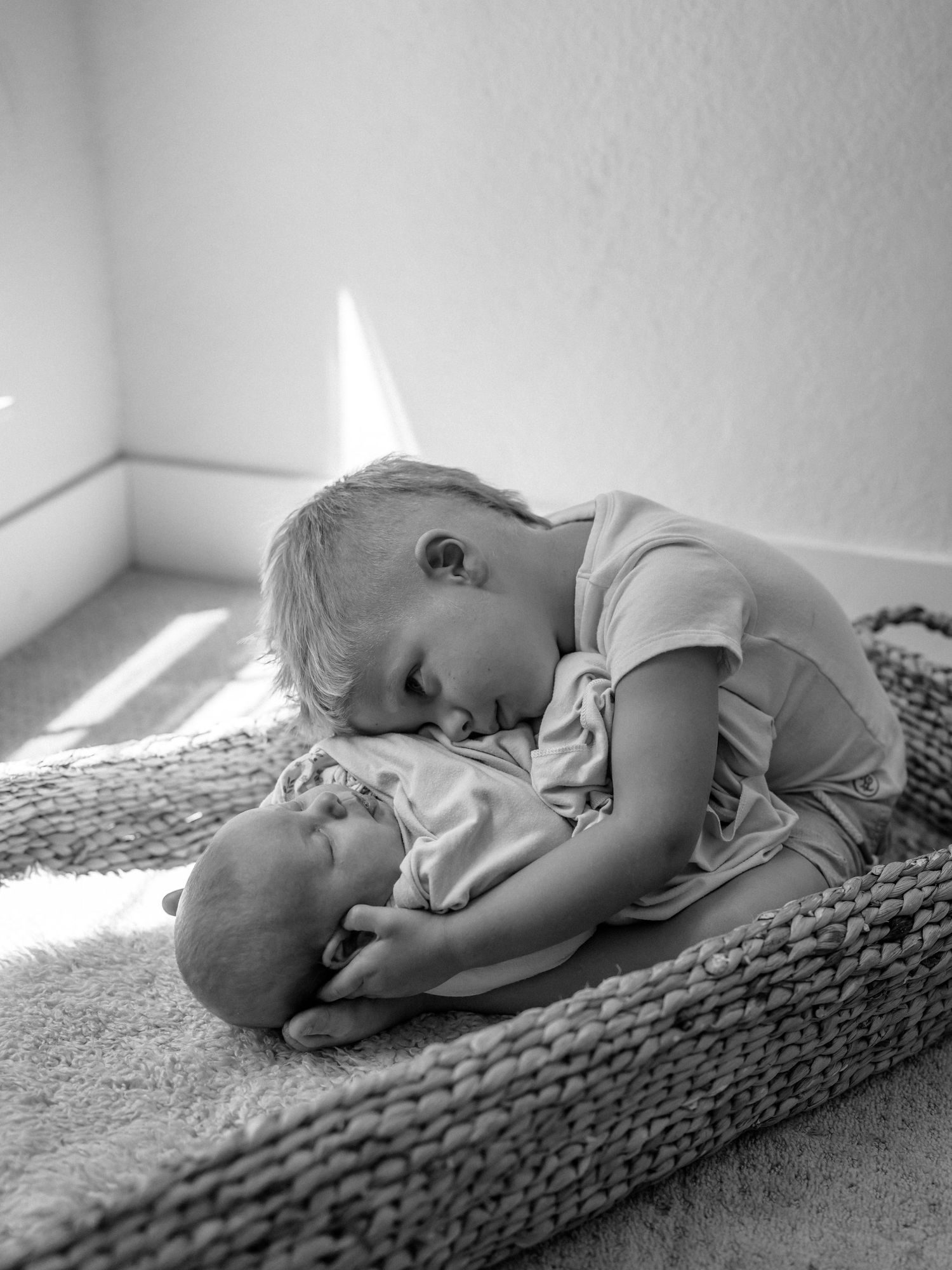 Black and white image of a sleeping baby on textured blanket in natural light.