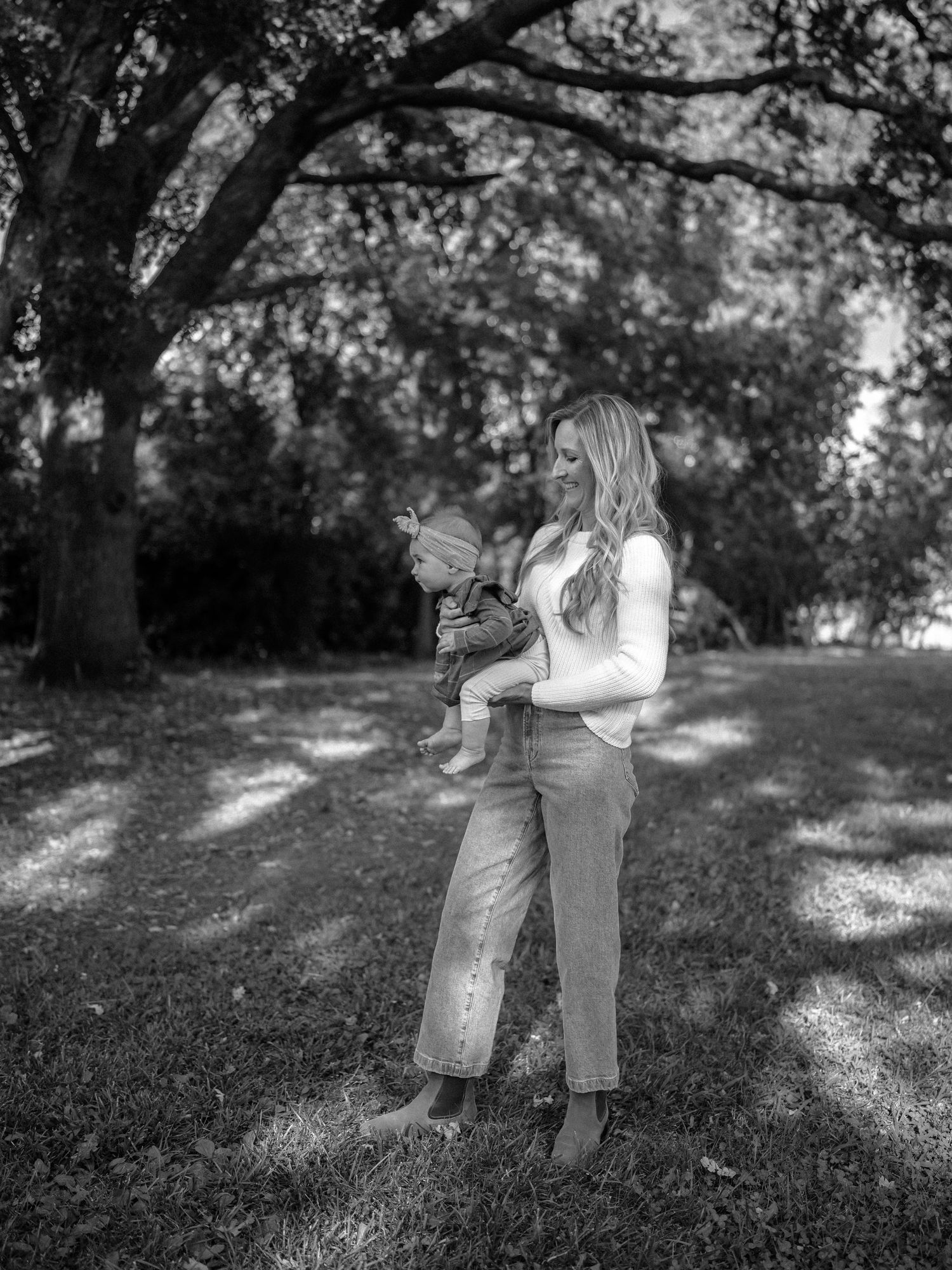 Black and white photograph of people walking together in a sunlit grassy area.