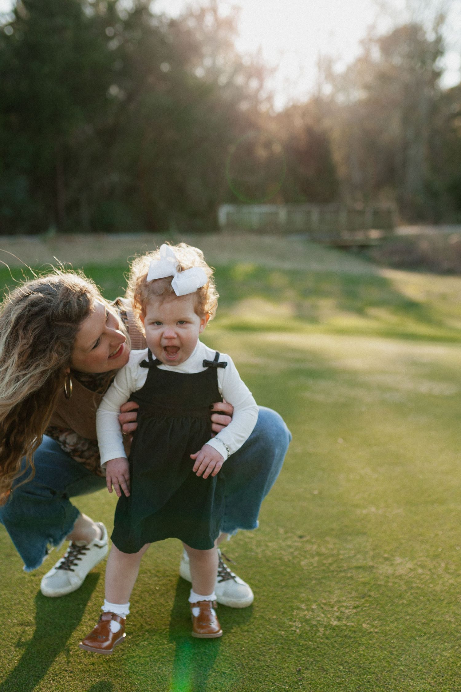 Parent and child sharing a playful moment together on a sunny lawn. Alabama photographer; South Alabama photographer