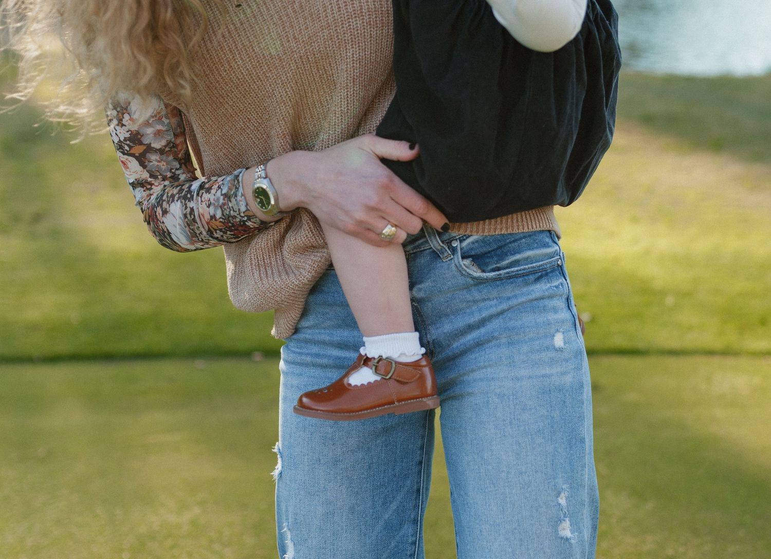 Detail shot of denim jeans and small brown shoes against grass. Alabama photographer; South Alabama photographer