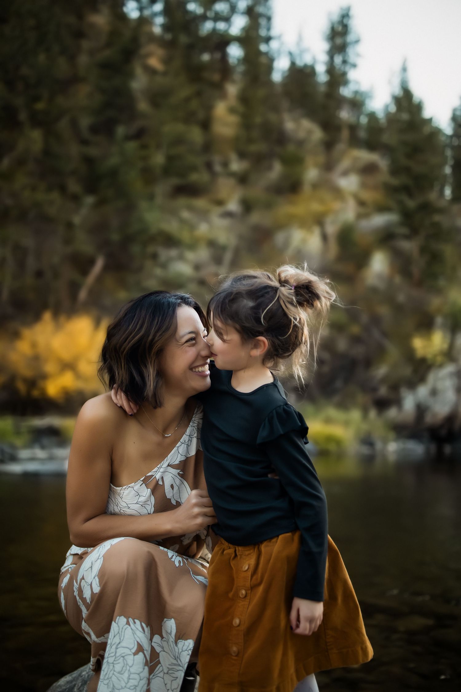 A sweet moment shared between parent and child by a lake with fall colors.