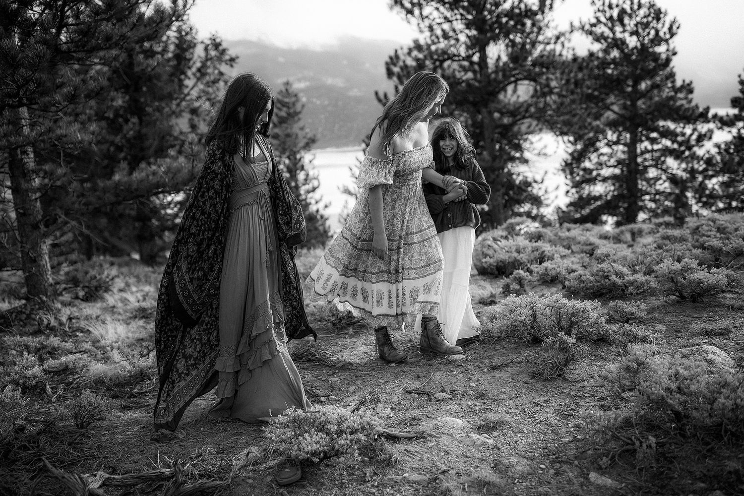 Family walks together through a scenic mountain landscape during an outdoor photo session.
