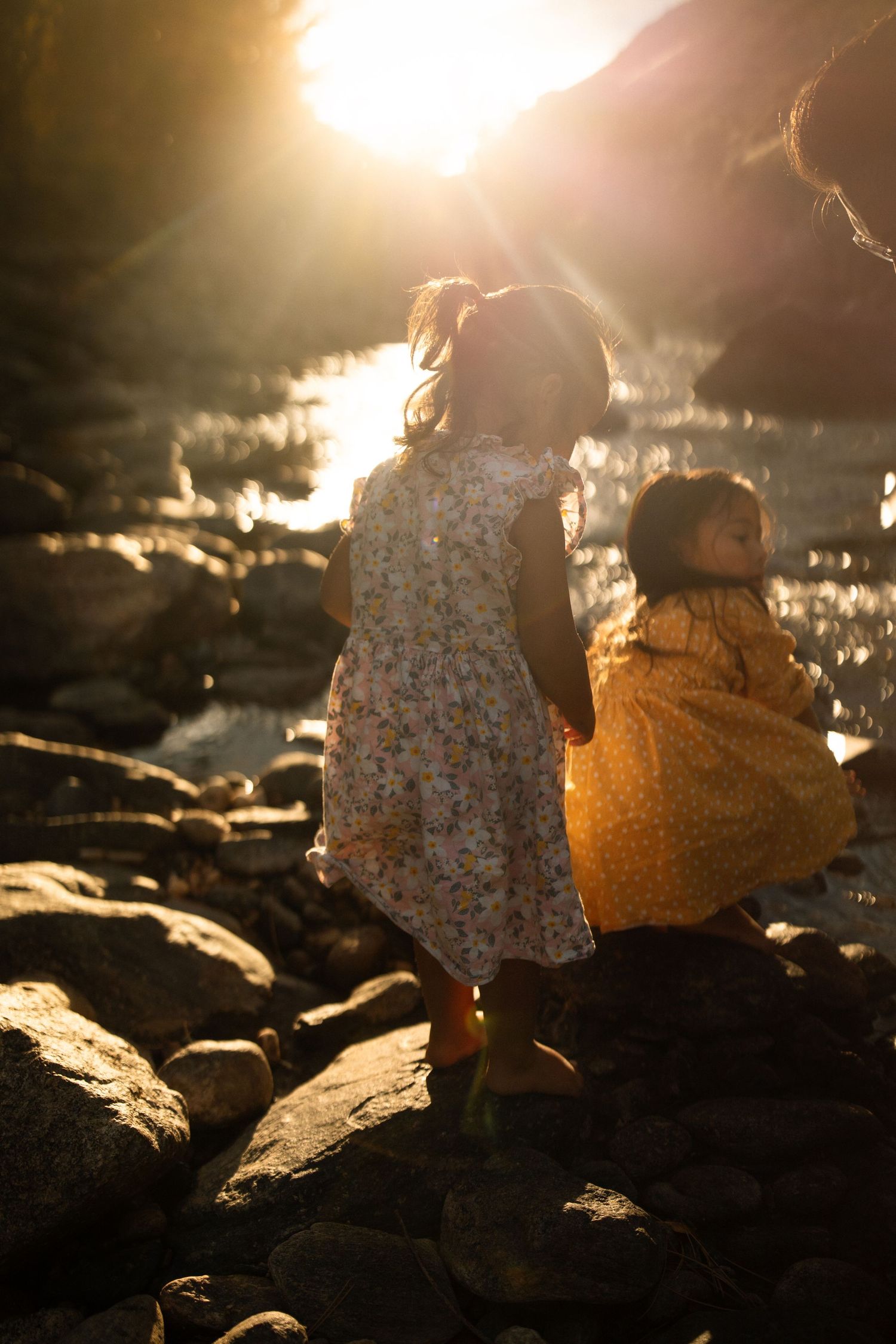 Silhouettes against golden sunlight on rocky terrain during sunset.