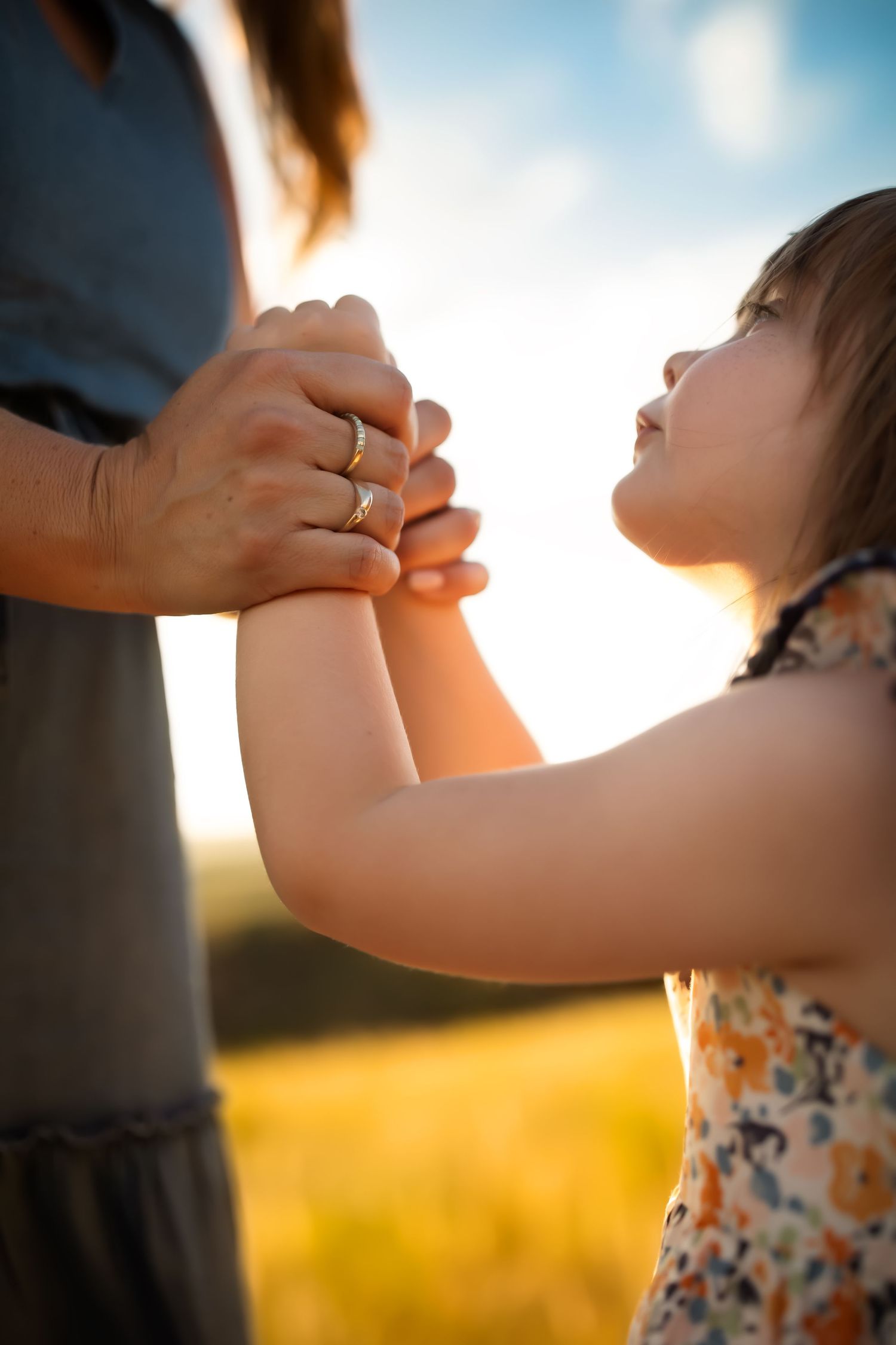 Holding hands against golden sunlit background in a tender moment.
