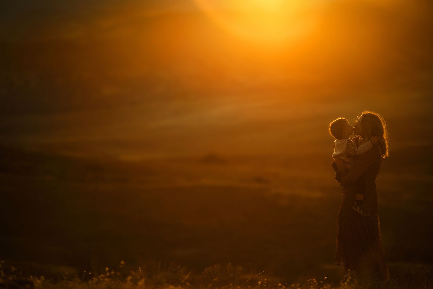 Dramatic orange sunset sky with silhouetted landscape creating a warm atmospheric scene.