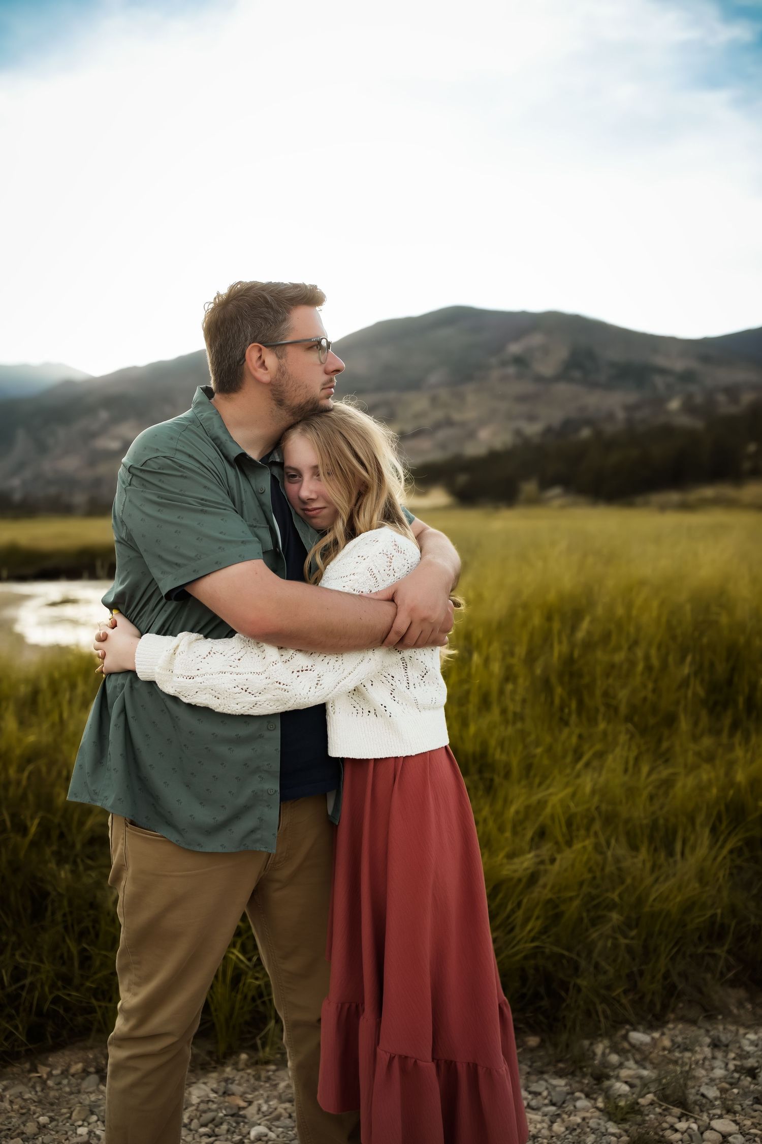 A tender embrace captured in a mountain meadow at golden hour.