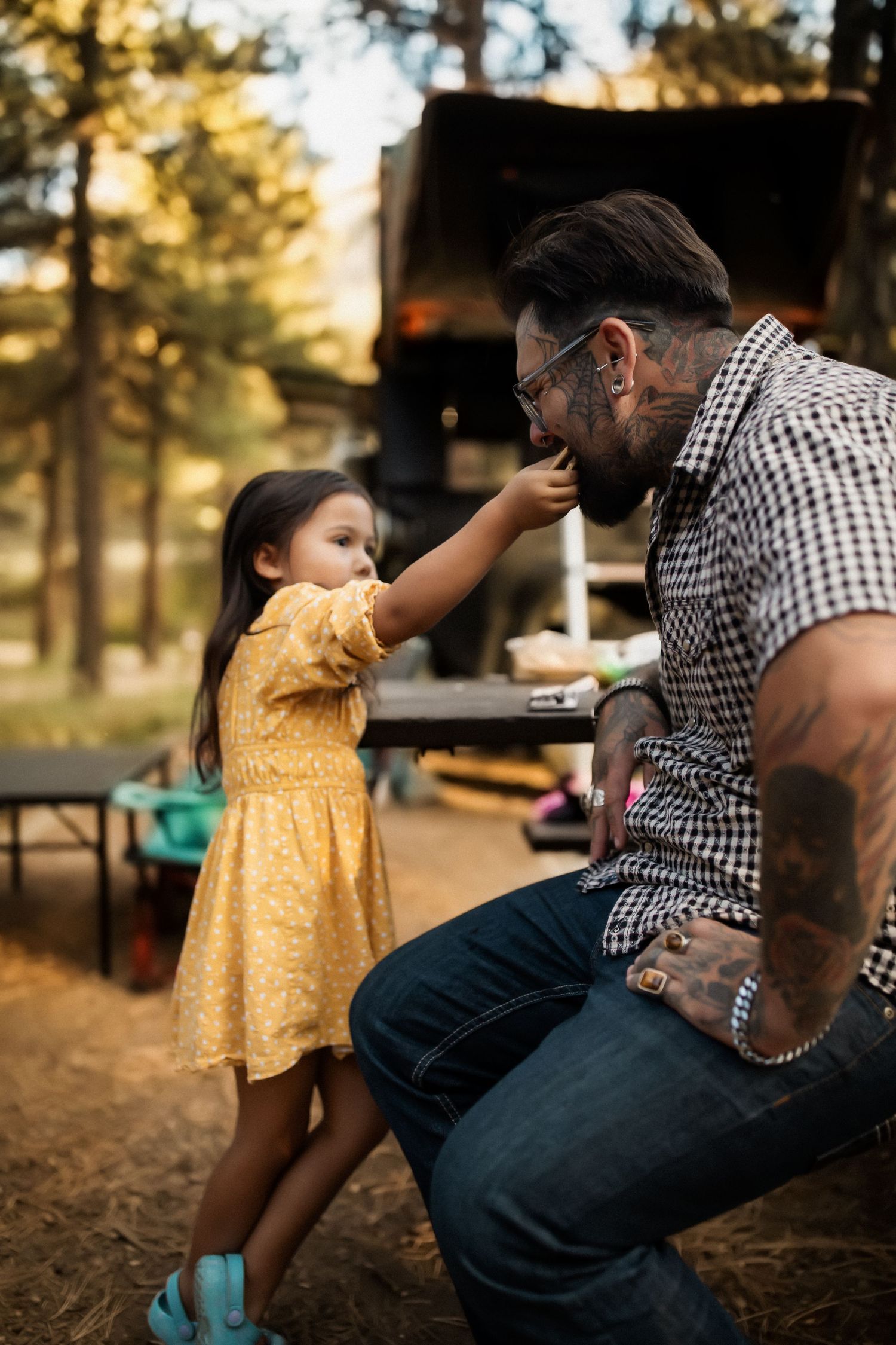 Outdoor playtime scene with adult in checkered shirt and child in yellow dress at sunset.