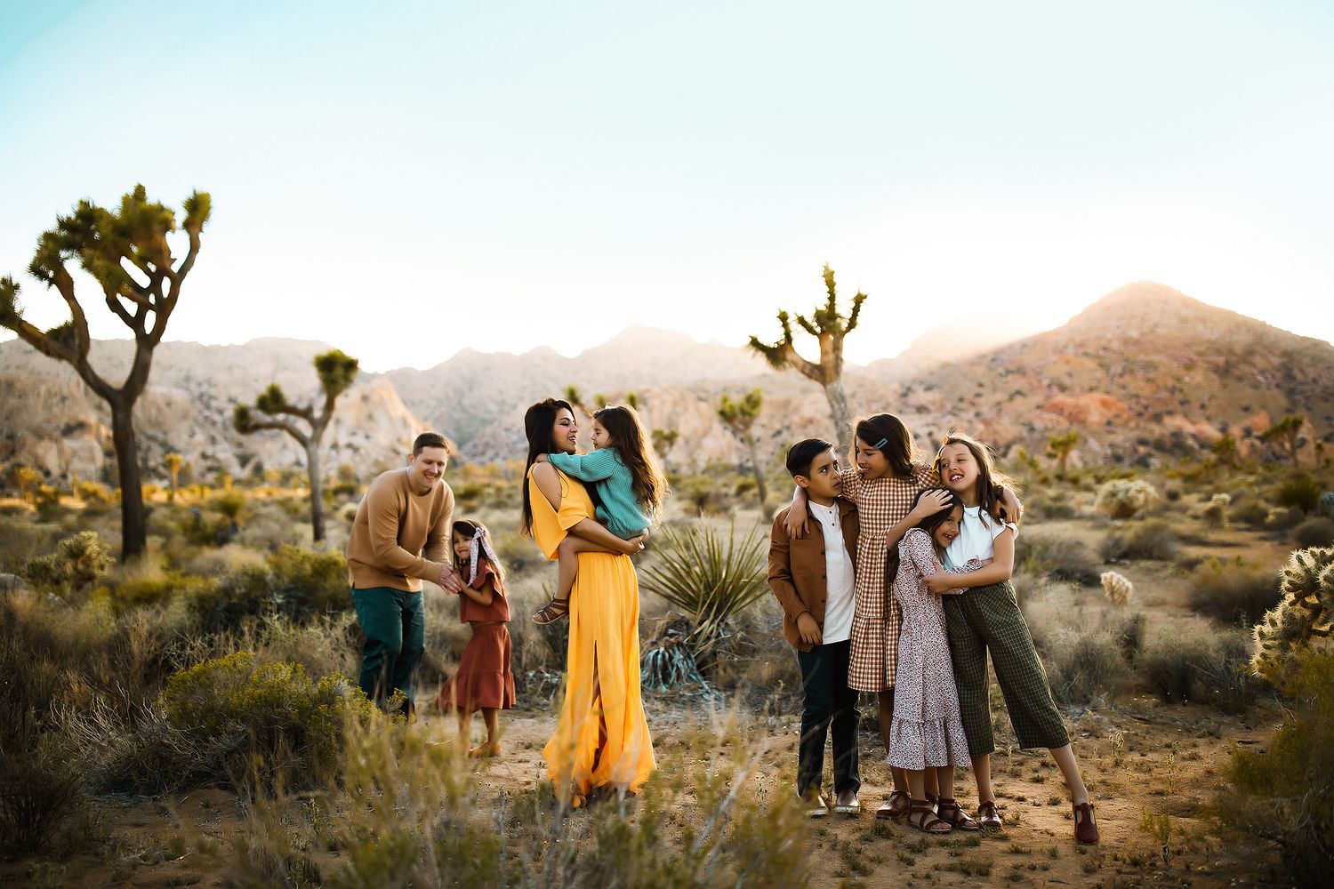Group gathering in Joshua Tree National Park desert landscape during golden hour among iconic desert plants.