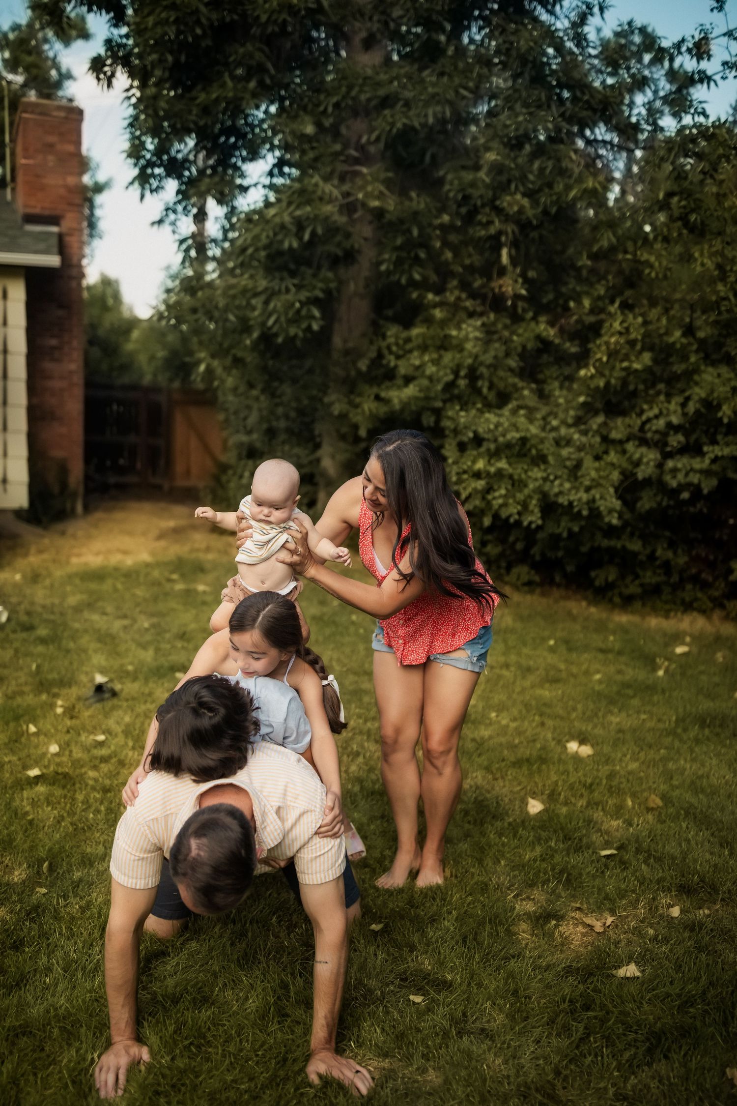 A playful family moment in a backyard with trees in the background.