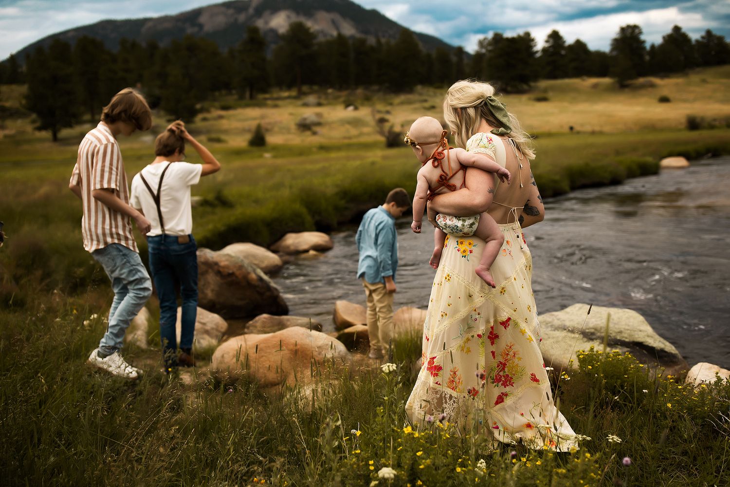 Candid family photos taken by a stream in a mountain meadow on a sunny afternoon.