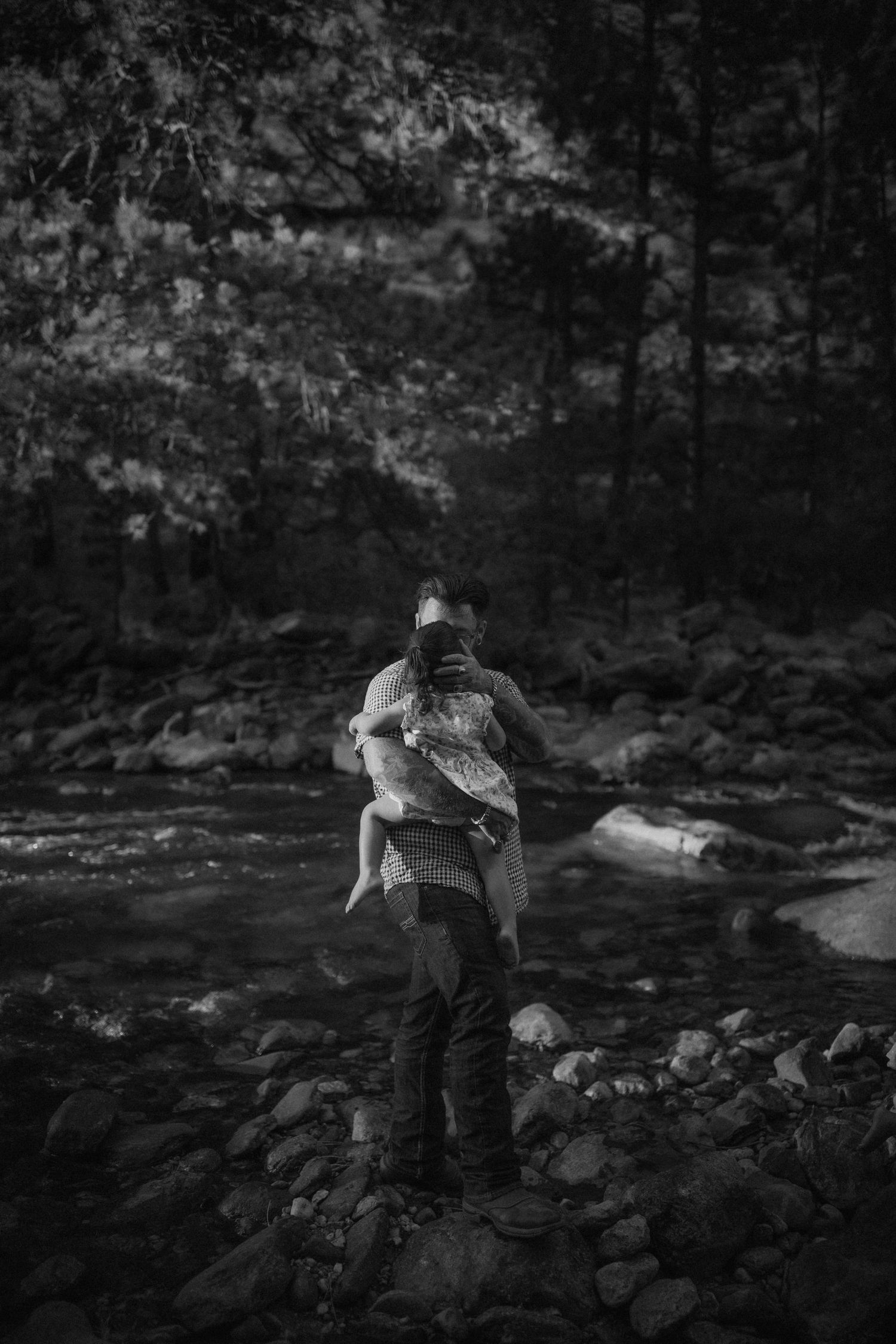 A black and white photo series shows someone exploring a rocky stream bed in a wooded forest setting.