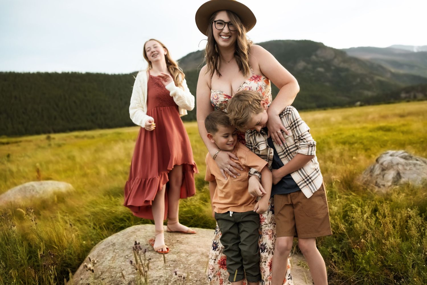 A family enjoys a scenic mountain hike together on a sunny autumn day in the rolling green hills.