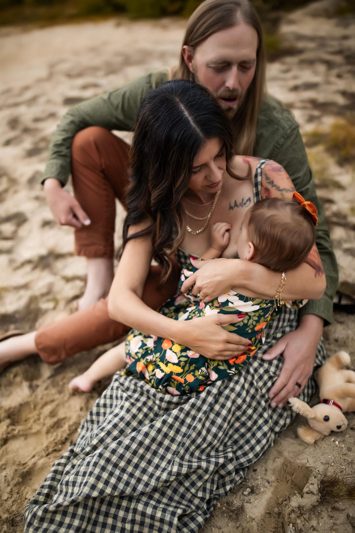 Family cuddles together on a rocky surface while wearing casual clothing.