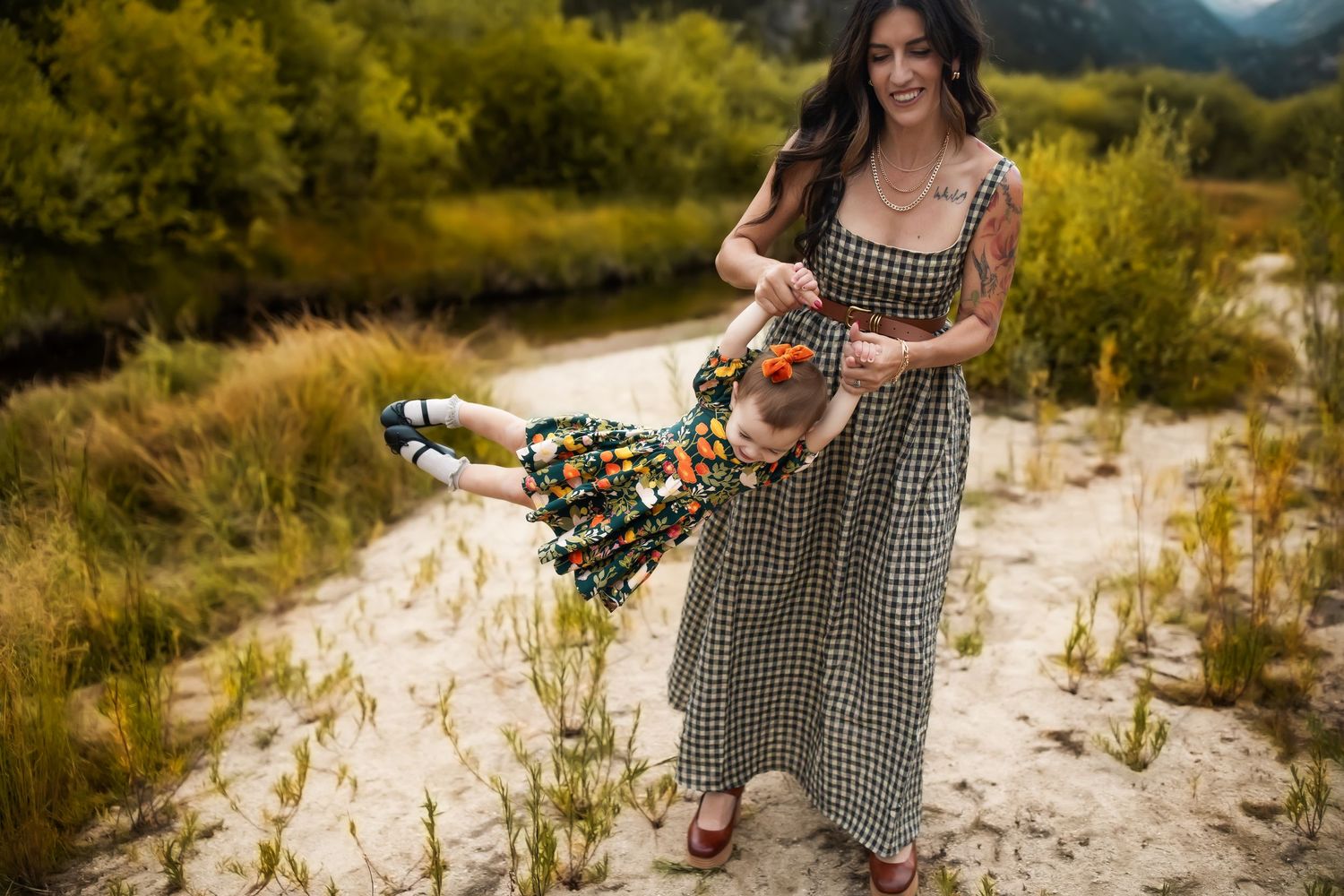 A person in a gingham dress walks through a sunny meadow holding wildflowers on a summer afternoon.