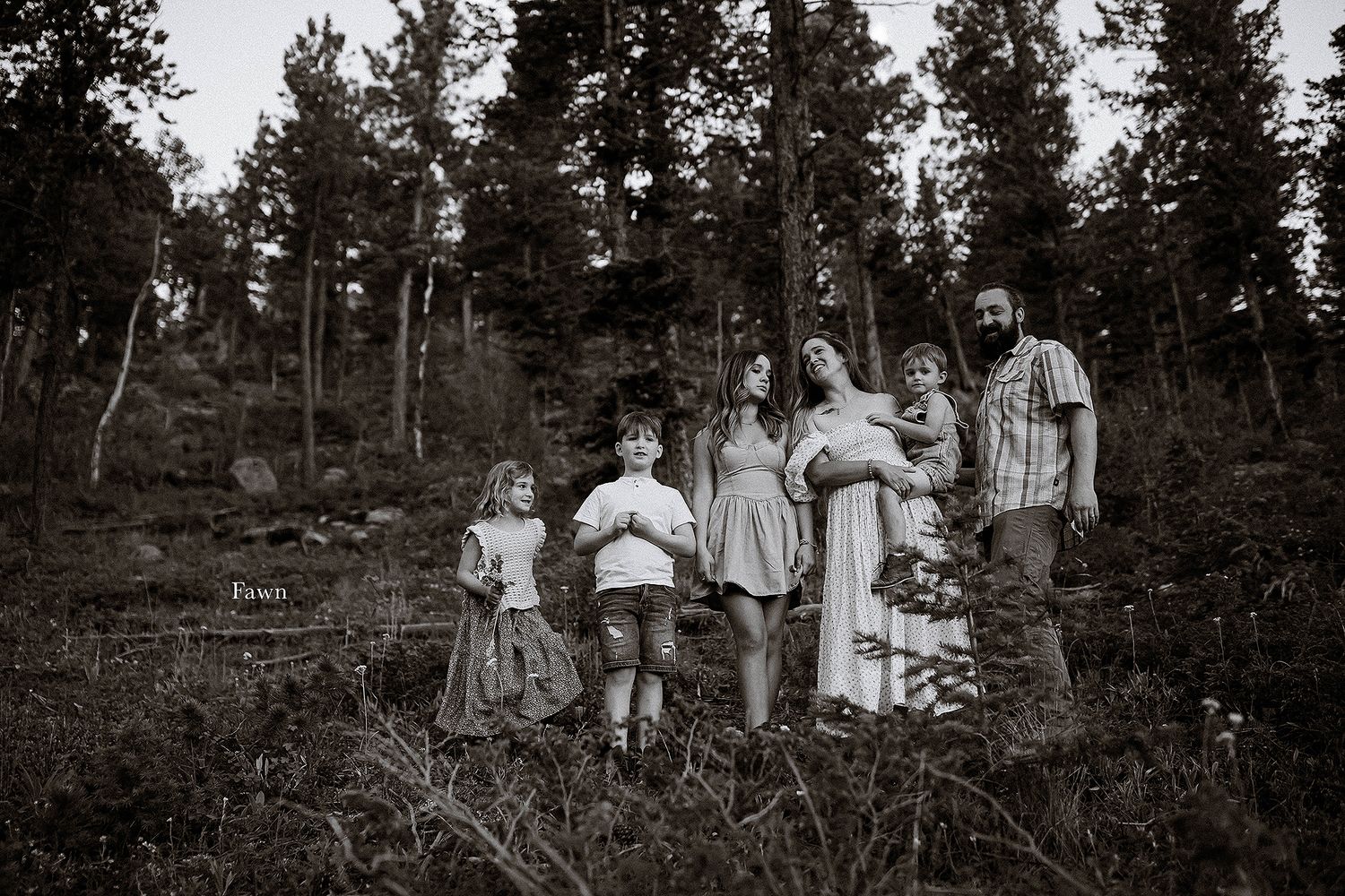 Group gathered in wooded area with tall pine trees in black and white.