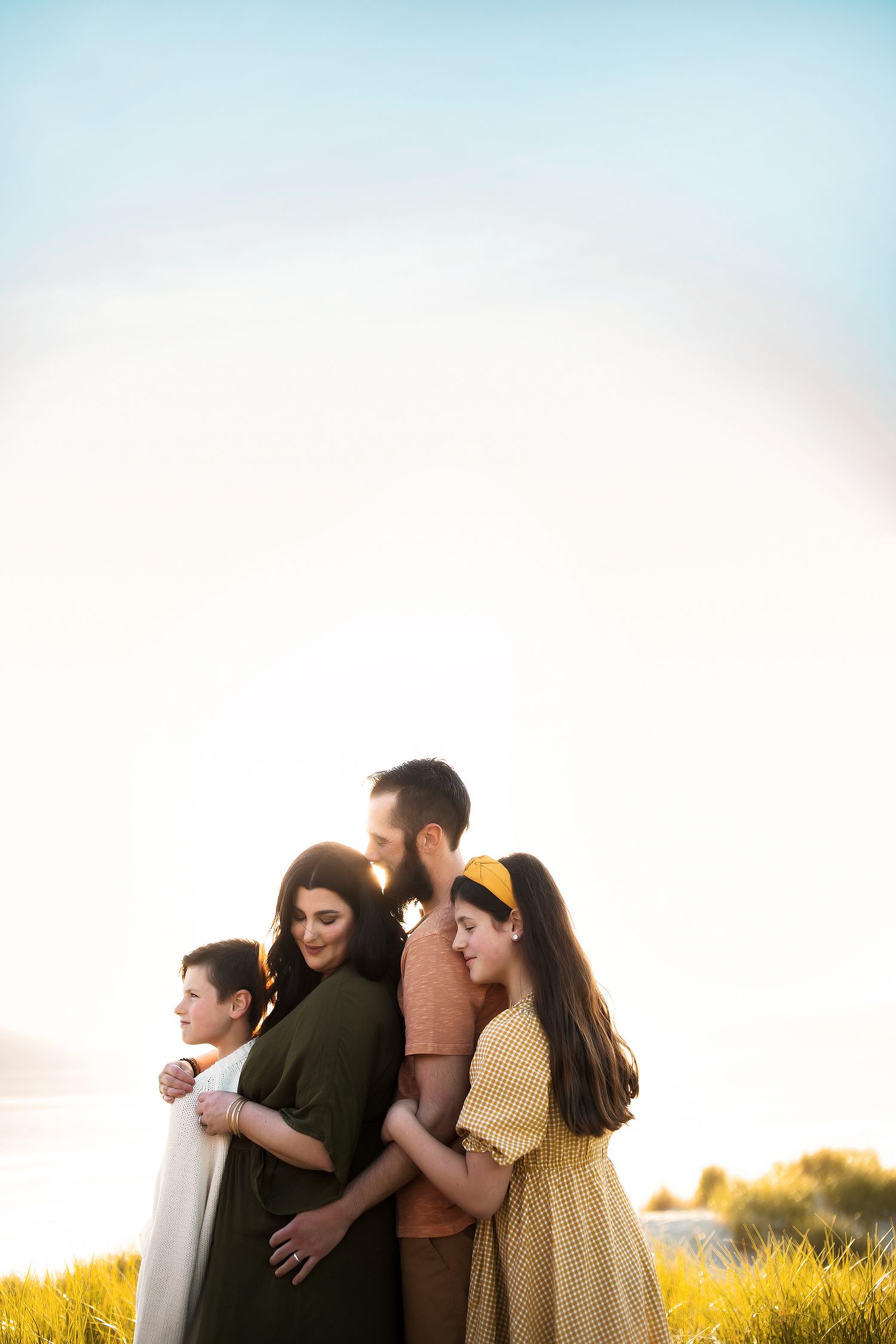 Family group enjoying sunset together in golden field.
