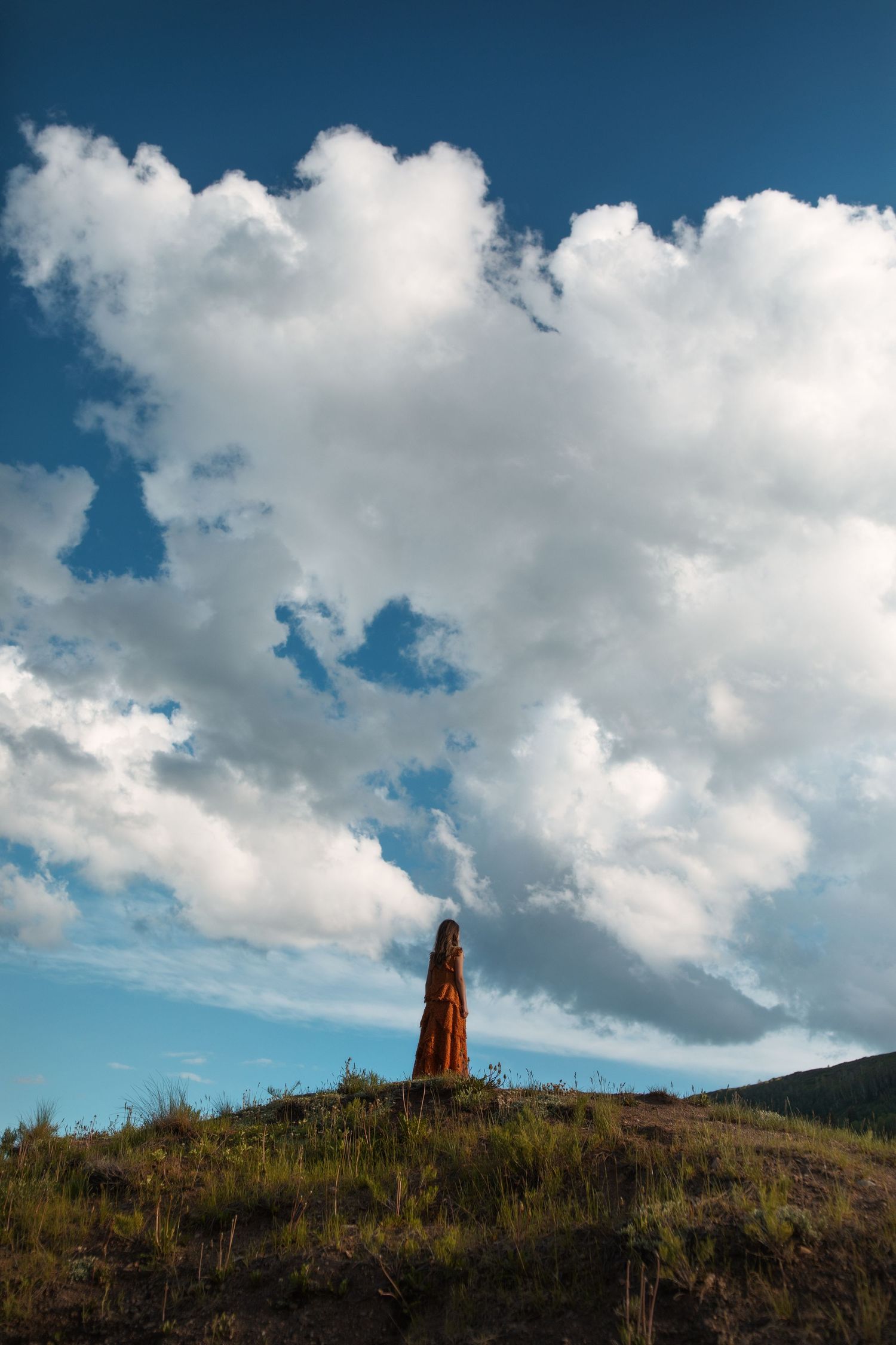 A series of landscape photos showing a stone monument on a hilltop against dramatic blue skies with white puffy clouds.