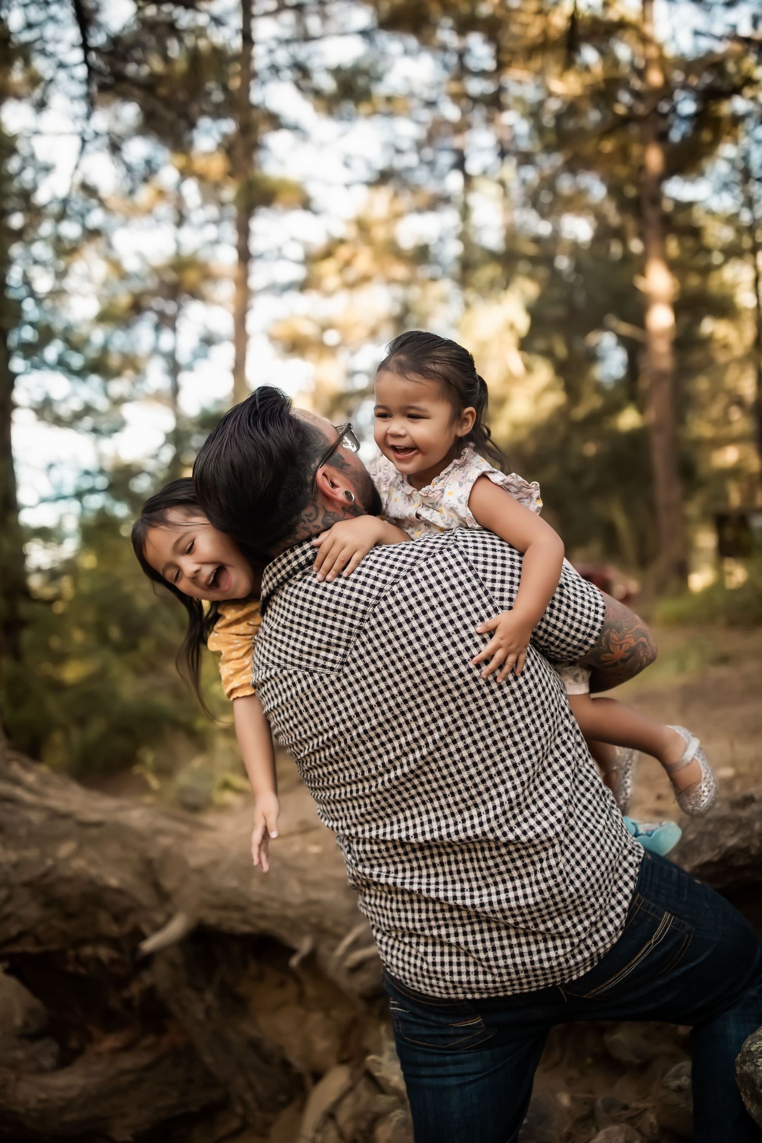 Playful family moment captured in a forest setting with joyful expressions.