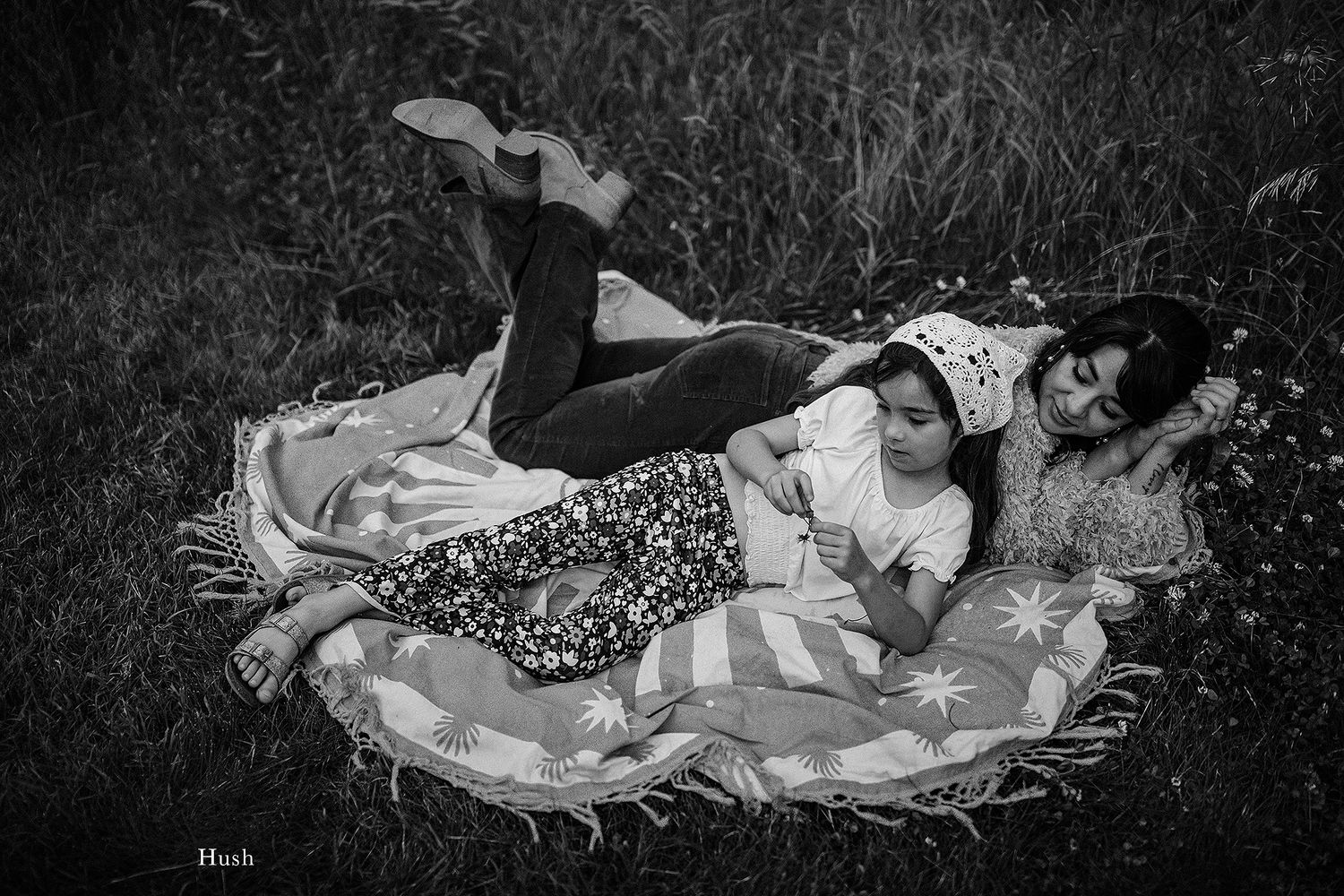 People lounging on blankets in grass shown in artistic black and white composition.