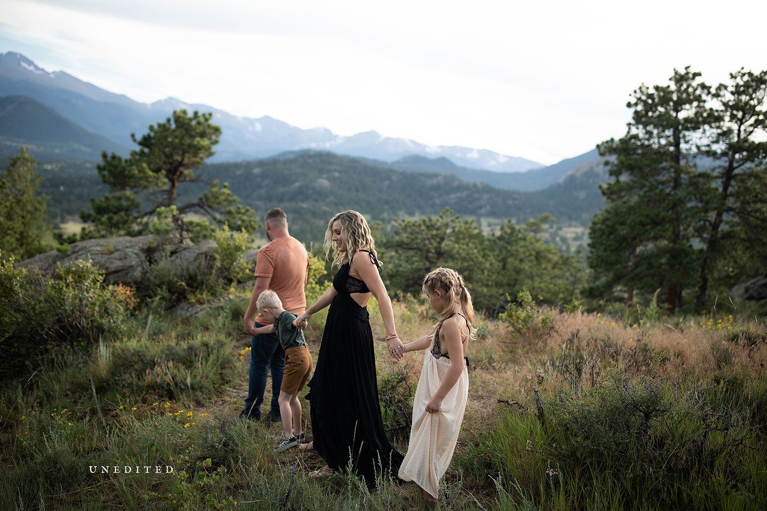 Group walking along a mountain ridge with scenic mountain views in the background.